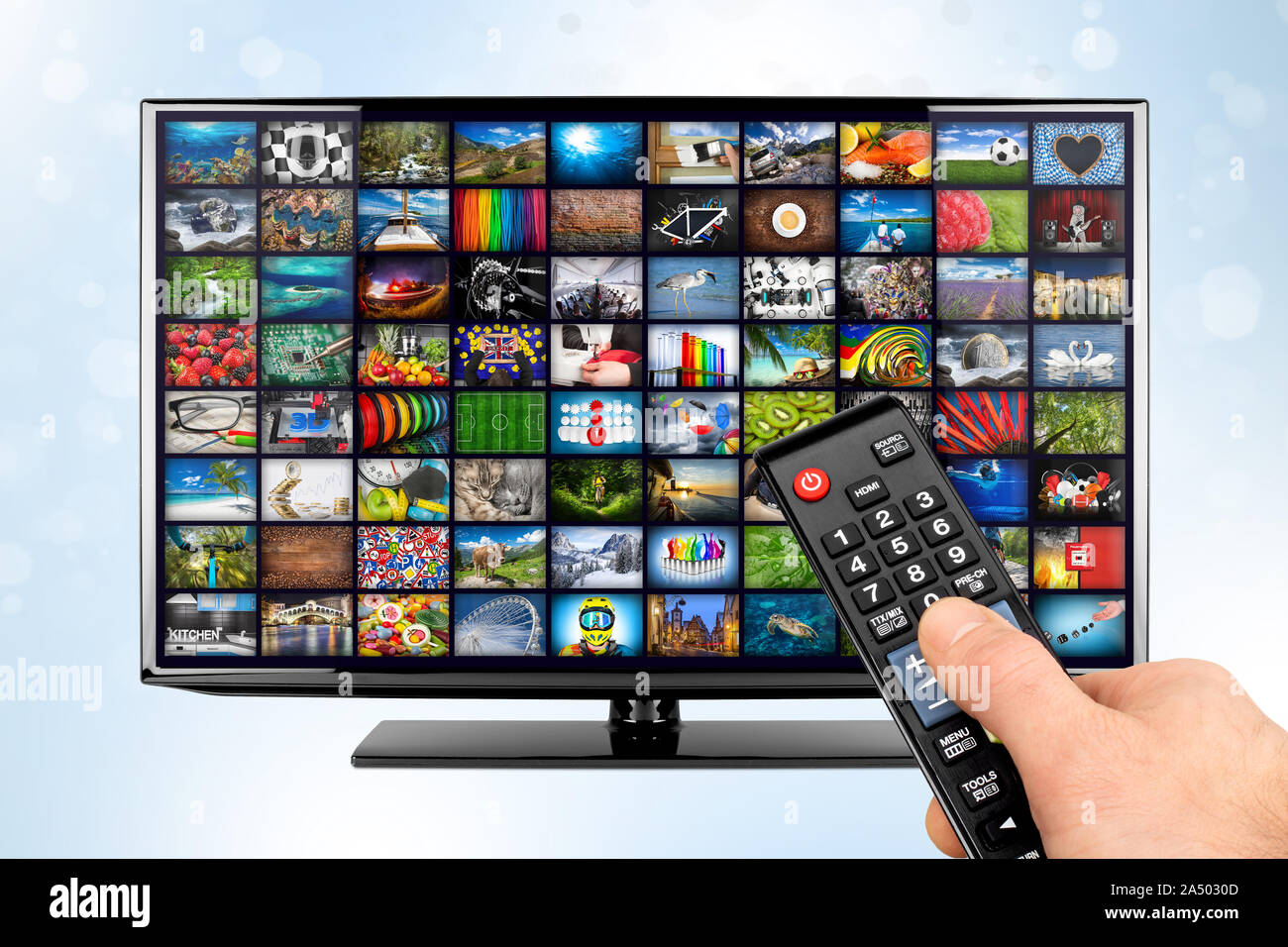 hand with remote on black flat tv screen display with picture movie gallery backdrop. television in front of white blue bokeh background. Computer mul Stock Photo