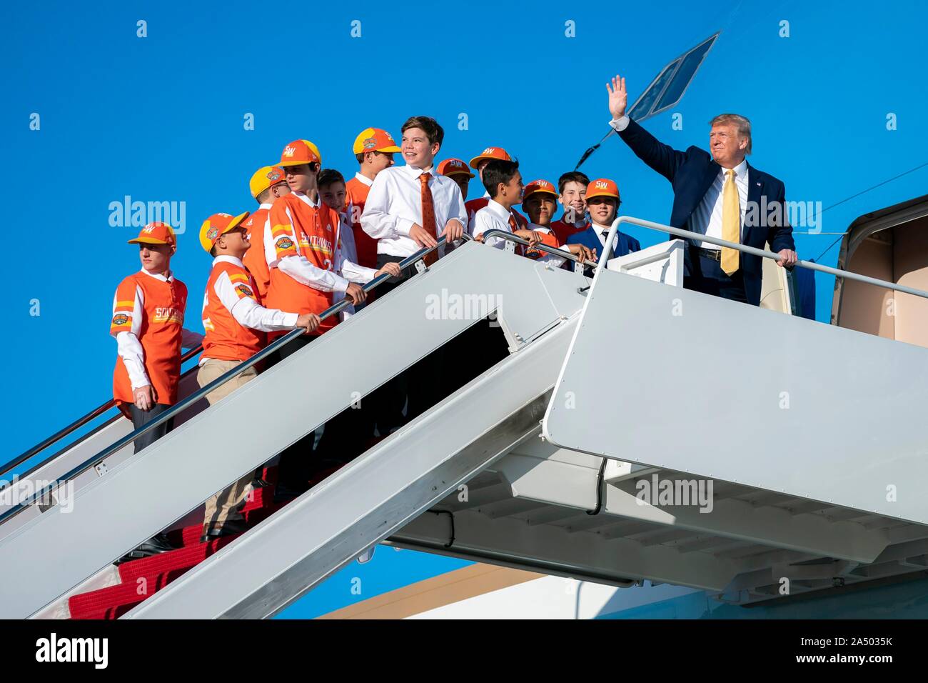 U.S President Donald Trump waves as he boards Air Force One with members of the Little League World Series champs Eastbank All-Stars little league baseball team from Louisiana at Joint Base Andrews October 11, 2019 in Clinton, Maryland. The president is giving the team a ride home aboard Air Force One. Stock Photo
