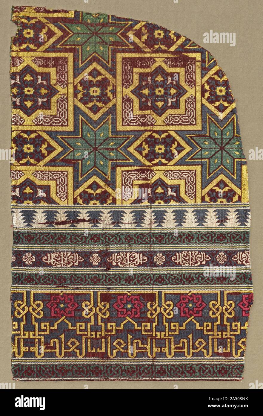 Alhambra hanging fragment with decorated bands, 1300s. The ability to combine different designs and colours harmoniously was one of the unparalleled achievements of Islamic art. This silk curtain fragment reveals juxtapositions of large and small scaled designs with curving and angular lines, all woven with bold colours in bands of varying widths. The contrasts are featured in the upper design of large squares positioned to form eight-pointed stars, in the narrow band with ivory-silk cursive script offering &quot;good fortune and prosperity,&quot; and in the wide band with large yellow-silk ku Stock Photo