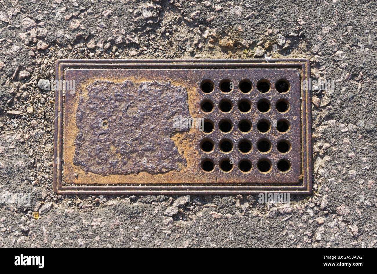Old drain or water supply access cover on a pavement in the UK. Stock Photo