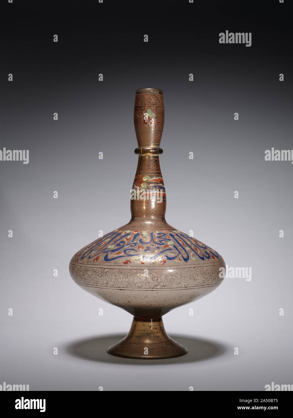 Bottle, c. 1900. The bold inscription on the body of the bottle translates: &quot;Glory to our lord, the sultan, the king, the victorious, the protector of the world and the religion, Muhammad.&quot; This is the same Mamluk sultan, Muhammad ibn Qalaun referred to on the mosque lamp. Stock Photo