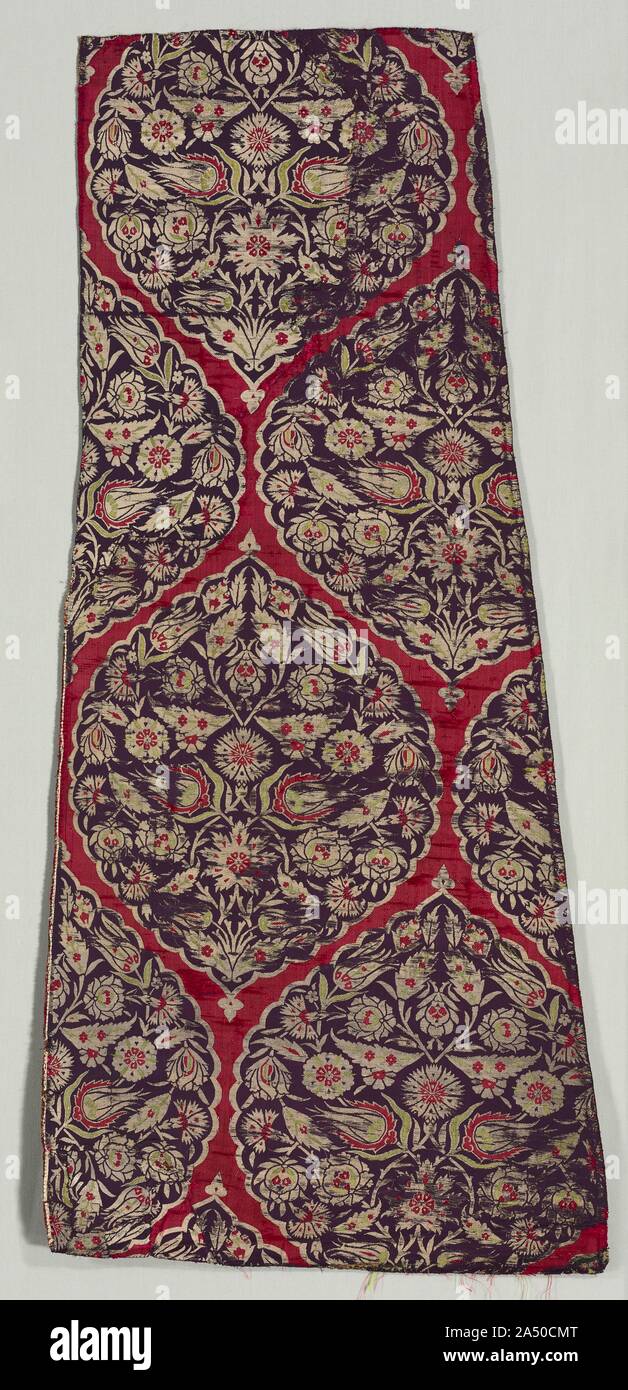 Brocaded silk with foliate medallions from a kaftan, 1525-1575. Medallions enriched with floral and foliate decoration were signature Ottoman patterns during the height of silk textile production in the second half of the 1500s. Imperial kaftans with related patterns are preserved in the Topkapi Palace Museum in Istanbul along with those worn by young princes. In this splendid length from a kaftan, abundant silver-thread flora and overlapping leaves on vines enliven medallions in the densely woven fabric. It is a combination of two weaves, called lampas, which creates two contrasting surfaces Stock Photo