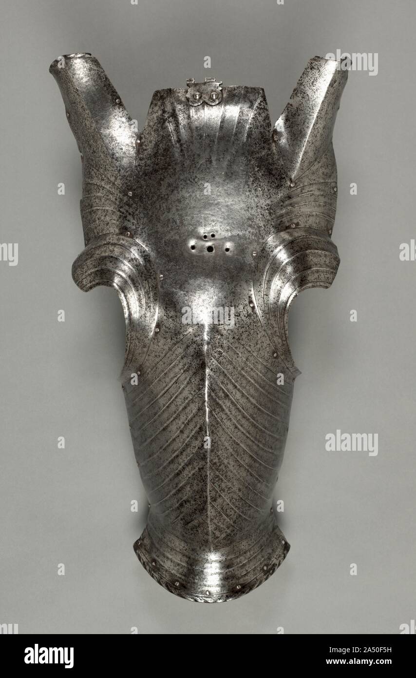 Chanfron in Maximilian Style, c. 1510. The chanfron was the primary element that protected and decorated a horse's forehead and face. It consisted of a plate of steel contoured to the horse's head from its ears to its nostrils. Normally, two holes were cut at each side of the forehead for the ears, and earpieces were sometimes riveted around their edges. This example, however, was forged in one piece. It belongs to the transitional period between the Gothic and the fluted armors introduced by Emperor Maximilian. The hinge at the top is for the attachment of the crest plate. Stock Photo
