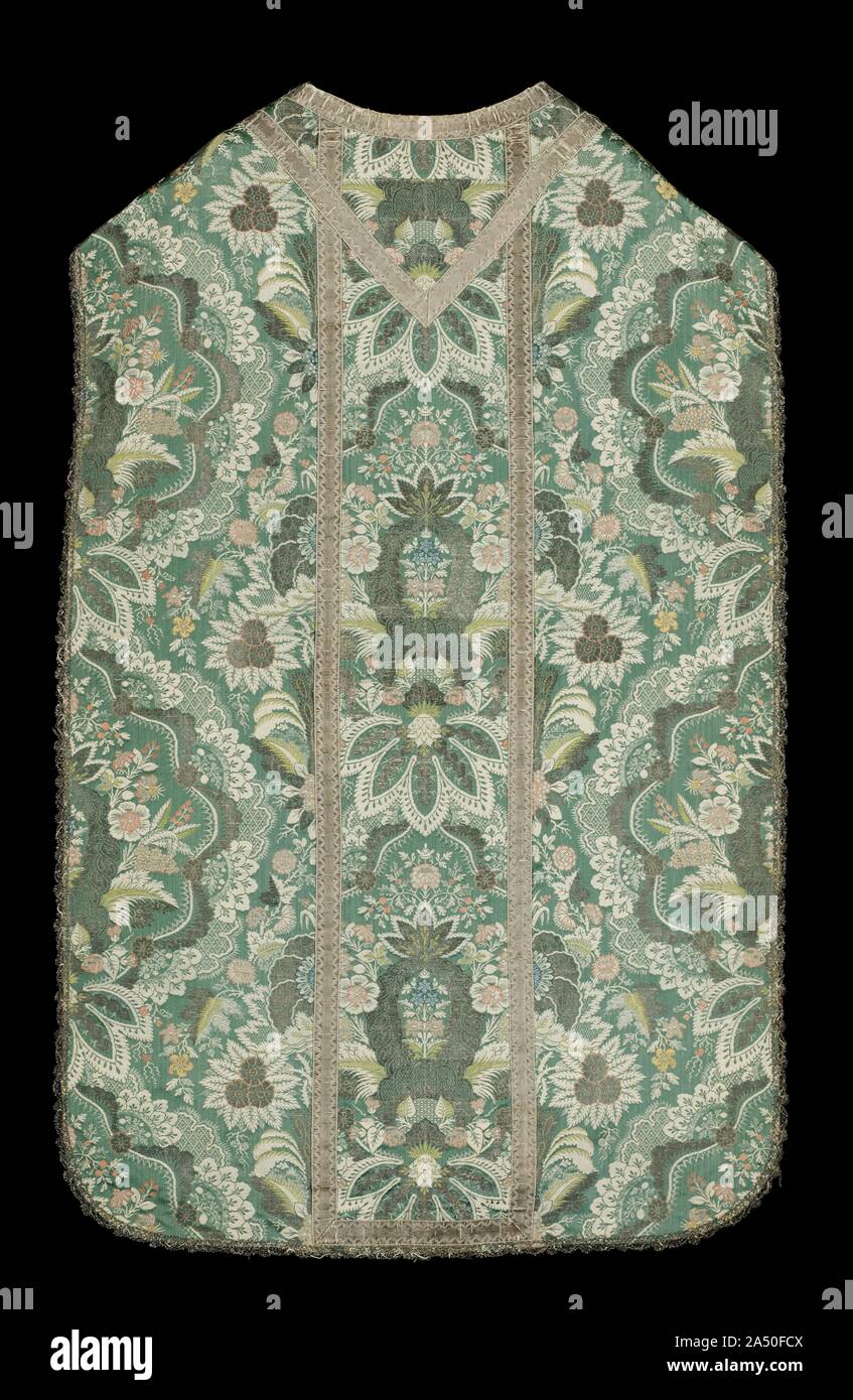 Chasuble, c. 1720s. The elegant formal design of blossoms and leaves in this woven silk is especially suitable for chasubles, liturgical vestments worn over albs with lace flounces and cuffs. Its small detailed ornament is reminiscent of prestigious lace, and is known as &quot;lace pattern.&quot; The division of the surface into three panels reflects the outmoded fashion of highlighting a different fabric in the center, often with religious images, called orphrey bands. In another change of ecclesiastical fashion, woven silks, such as this splendid example in the style of King Louis XIV (ruled Stock Photo