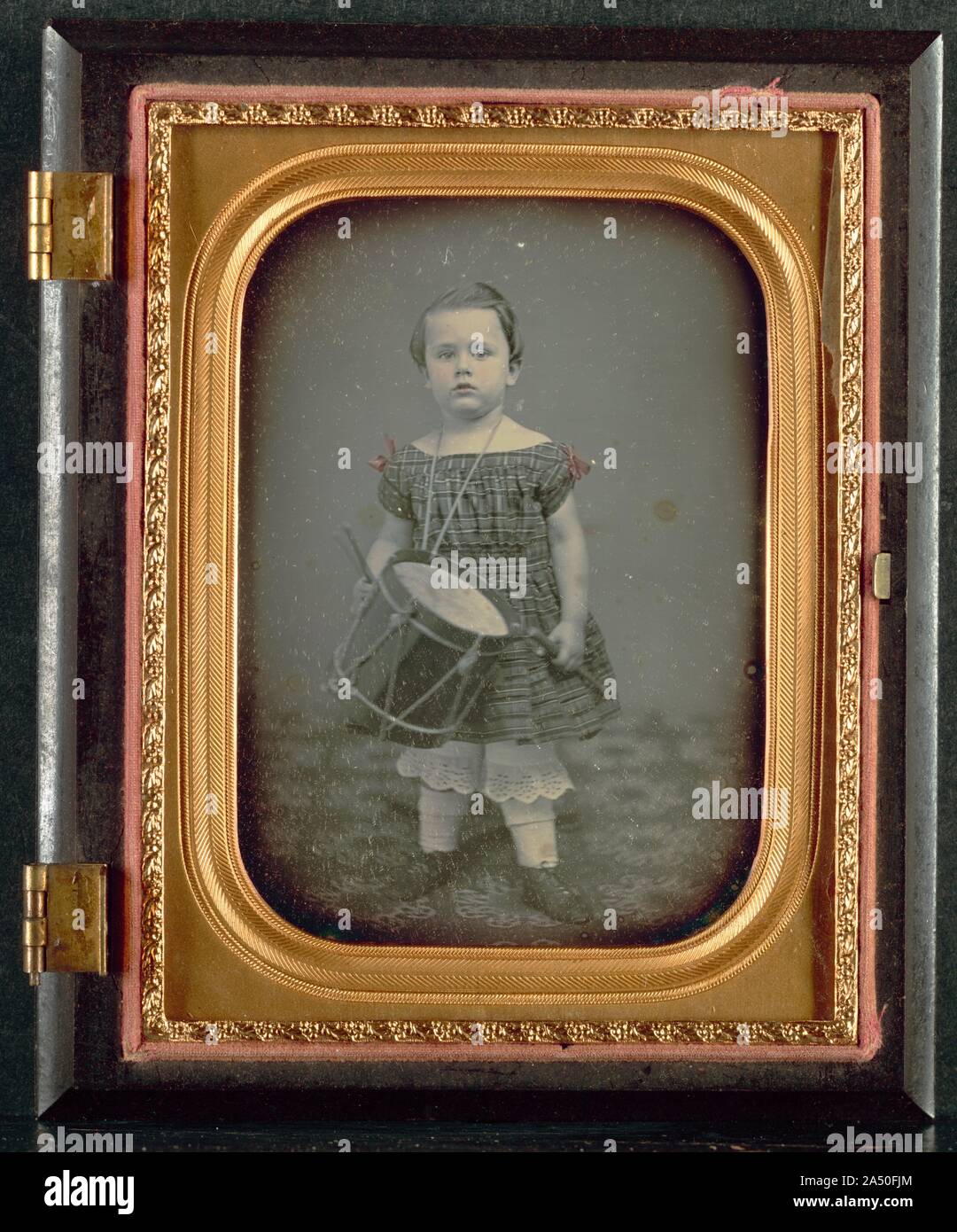 Child with Drum, 1850s. For this finely toned daguerreotype, an unknown photographer skillfully manipulated a bulky camera into a low vantagepoint, ensured even lighting, and positioned the quaintly dressed subject against a neutral background to create a charming portrait. The child was carefully coached to stare directly into the lens and to hold the toy drum and drumsticks convincingly. Perhaps the drum is meant to recall earlier times in American history and to symbolize its fight for independence. Stock Photo