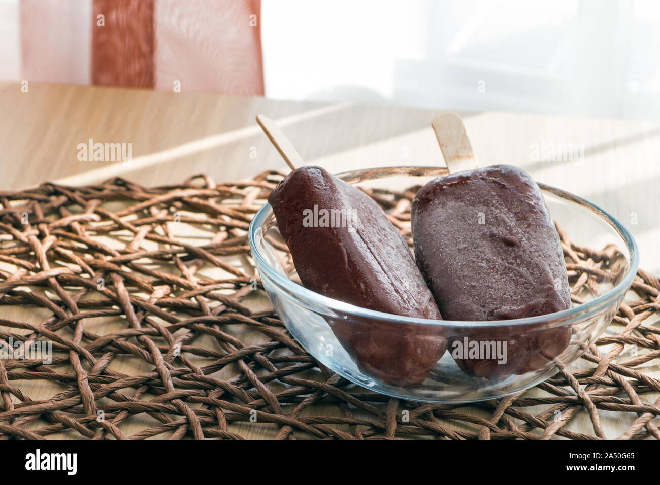 Delicious and healthy sweets. Fresh vegan raw food ice cream, just taken out of the freezer with hoarfrost on a chocolate surface. Glass bowl on the Stock Photo