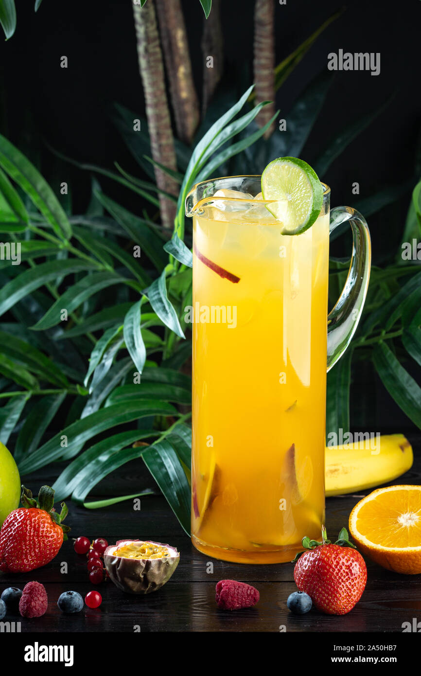 pineapple mango cocktail in a jug on a dark background with fruits Pineapple, Mango, Strawberry