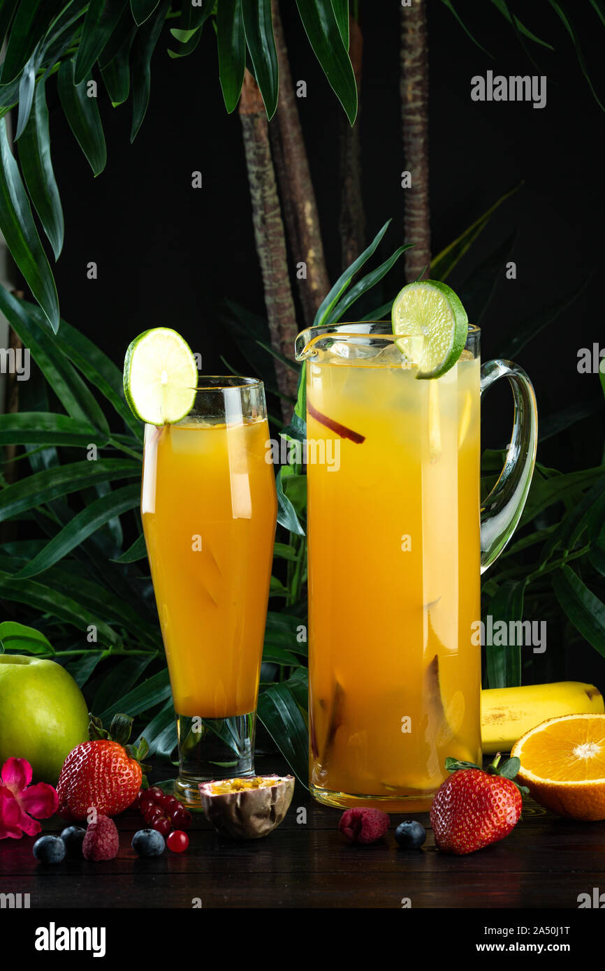pineapple mango cocktail in a jug and glass on a dark background with fruits Pineapple, Mango