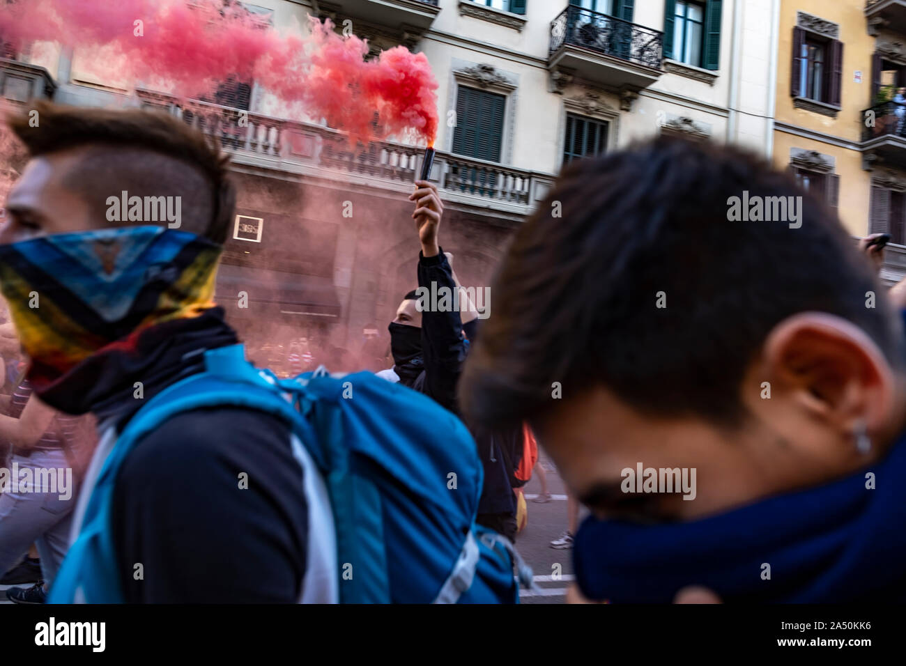 A protester holds a flare during the demonstration.Hundreds of protesters concentrated on the Gran Vía Street in Barcelona during the third day of protest following the sentences of the Spanish Supreme Court that condemns Catalan political prisoners to long prison terms. The demonstration culminated in front of the headquarters of the Department of Interior of the Generalitat with heavy police charges and barricades set on fire. Stock Photo