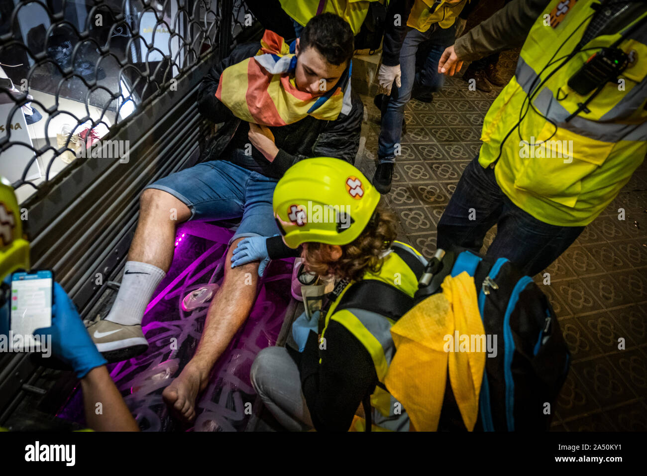 Medics attend to an injured protester during the demonstration.Hundreds of protesters concentrated on the Gran Vía Street in Barcelona during the third day of protest following the sentences of the Spanish Supreme Court that condemns Catalan political prisoners to long prison terms. The demonstration culminated in front of the headquarters of the Department of Interior of the Generalitat with heavy police charges and barricades set on fire. Stock Photo