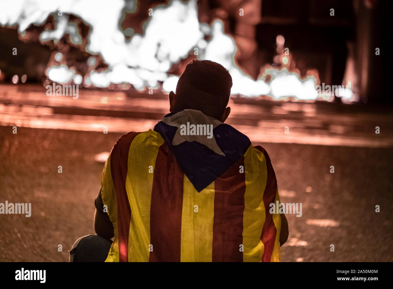 A protester sits in the middle of the road during the demonstration.Hundreds of protesters concentrated on the Gran Vía Street in Barcelona during the third day of protest following the sentences of the Spanish Supreme Court that condemns Catalan political prisoners to long prison terms. The demonstration culminated in front of the headquarters of the Department of Interior of the Generalitat with heavy police charges and barricades set on fire. Stock Photo