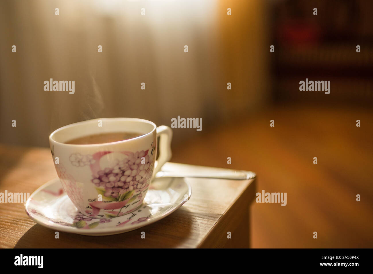 Black tea in an elegant vintage porcelain cup with steam on the table Stock Photo