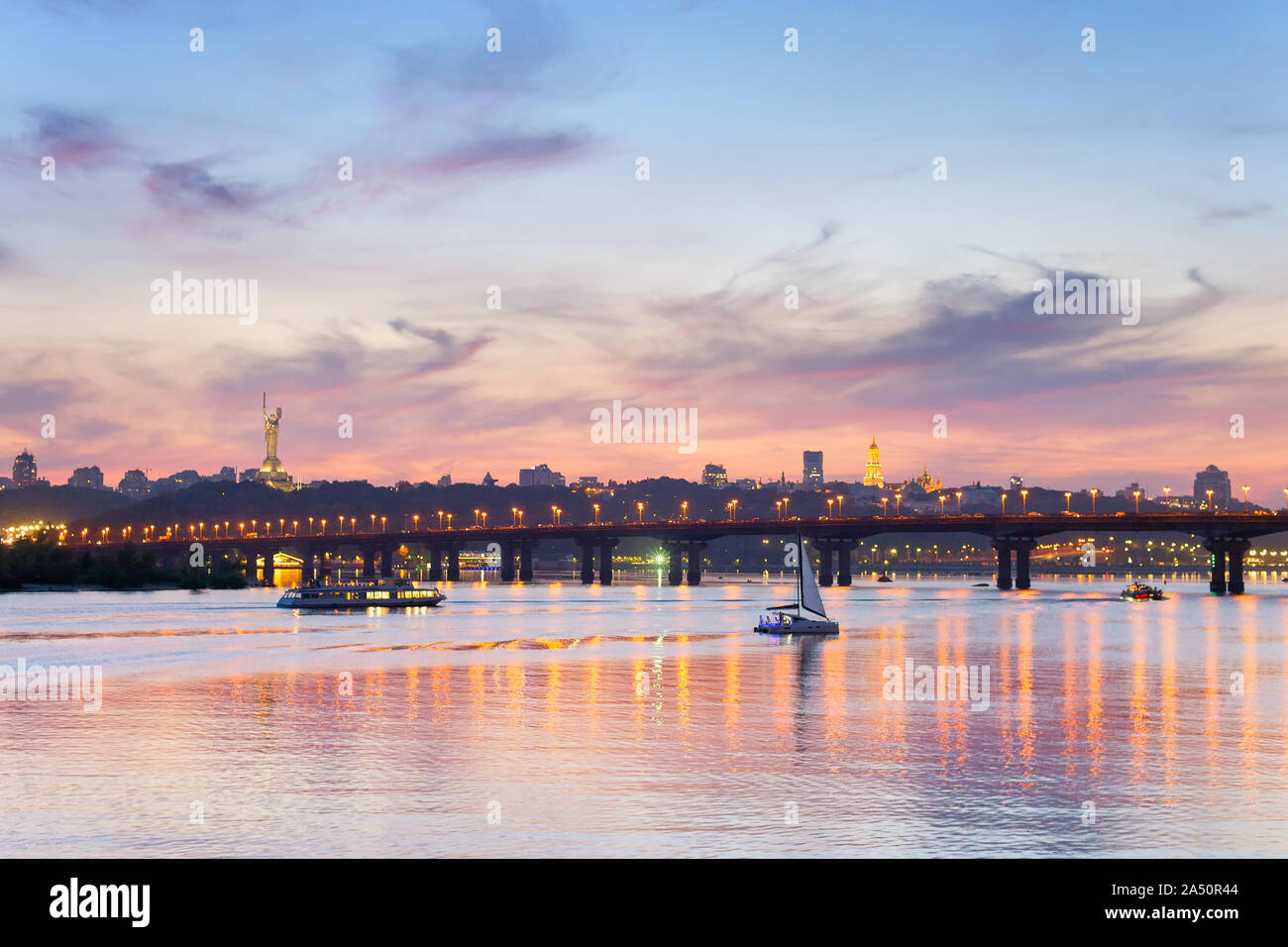 View of Mother Motherland monument above Dnipro river with Paton bridge and Kiev city at sunset, Ukraine Stock Photo