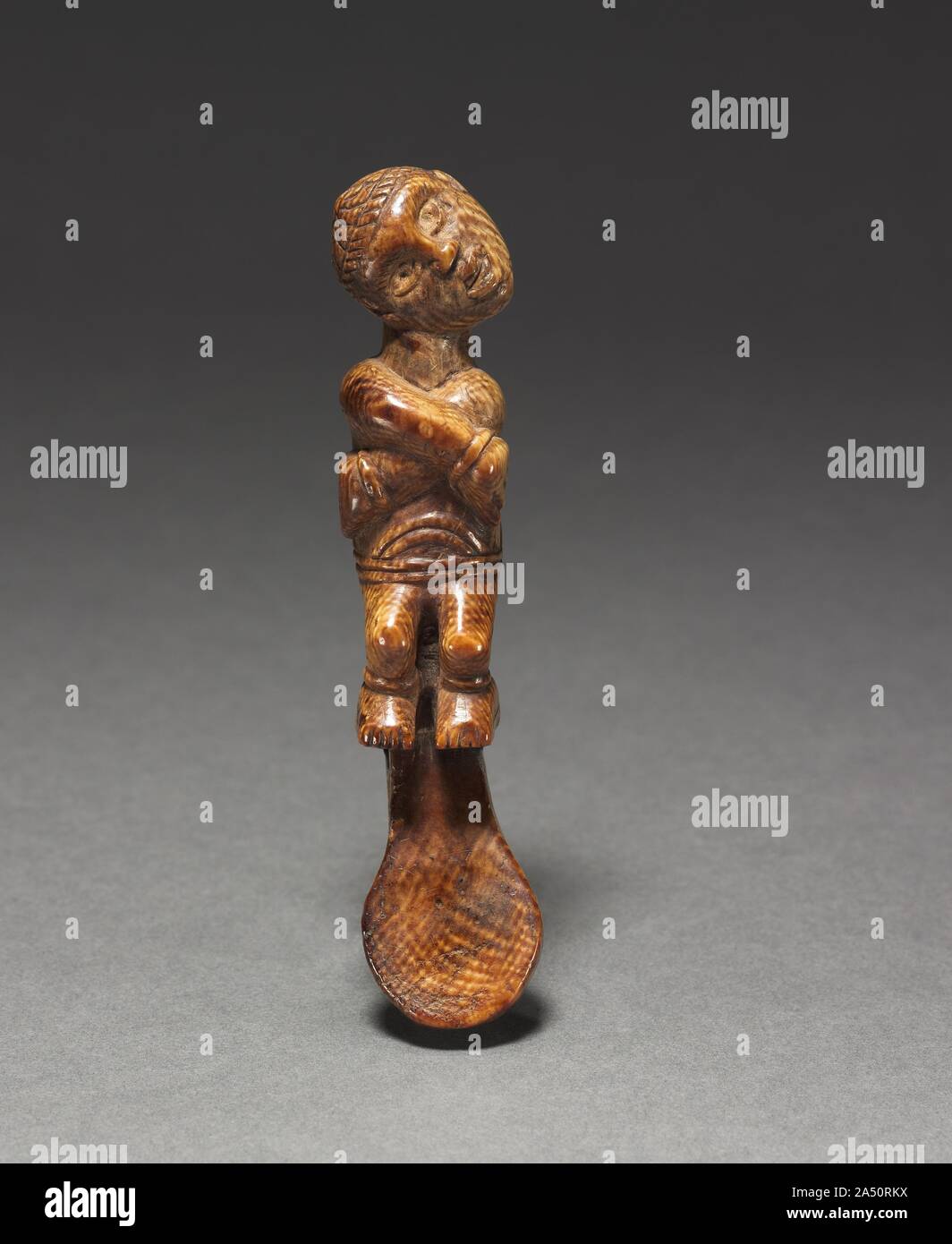 Female Figurine, late 1800s-early 1900s. This female figurine may be a fragment of a spoon or spatula, but this claim cannot be confirmed. Although the iconography of the human image is not uncommon in the art of the Yombe and related Kongo-speaking peoples, it does not reveal the object's function or purpose. The position of the arms has been interpreted as that of a bound prisoner while the head, tilted horizontally or at an angle, represents a broken neck or even a severed head, thus identifying the prisoner as a sacrificial victim. Yet, despite the large quantity of Yombe- and Kongo-attrib Stock Photo