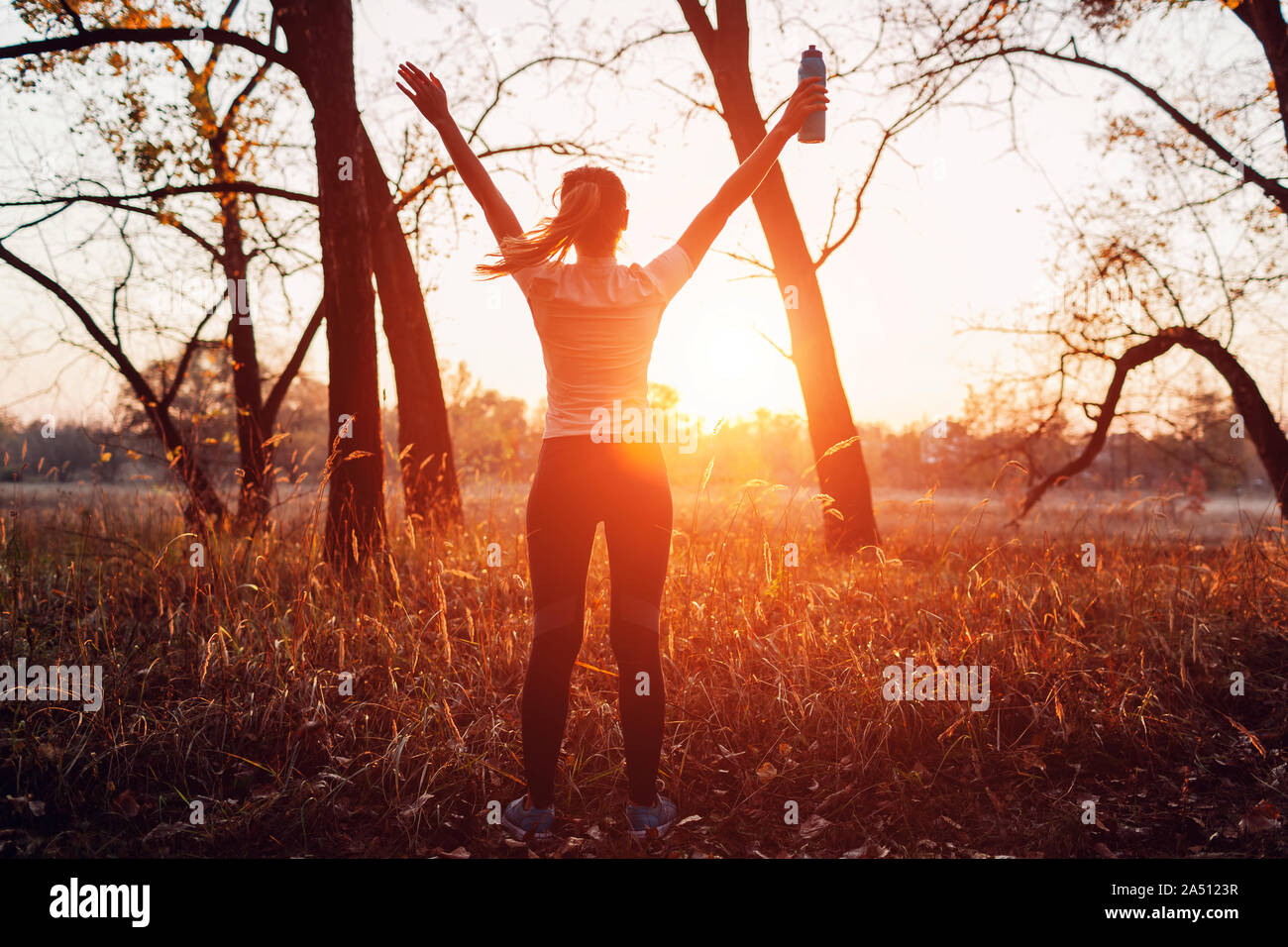 Runner raised arms after workout feeling free and happy succeeded in training. Woman admiring sunset. Healthy lifestyle Stock Photo