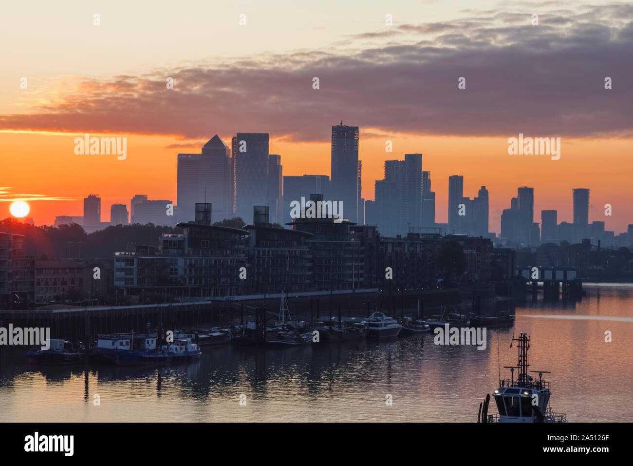 England, London, Docklands, Silouette of Canary Wharf Skyline and River Thames at Sunrise Stock Photo