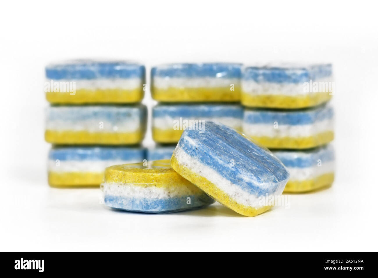Three-colored blue, white and yellow dishwasher cleaning tabs in self-dissolving foil on white background Stock Photo