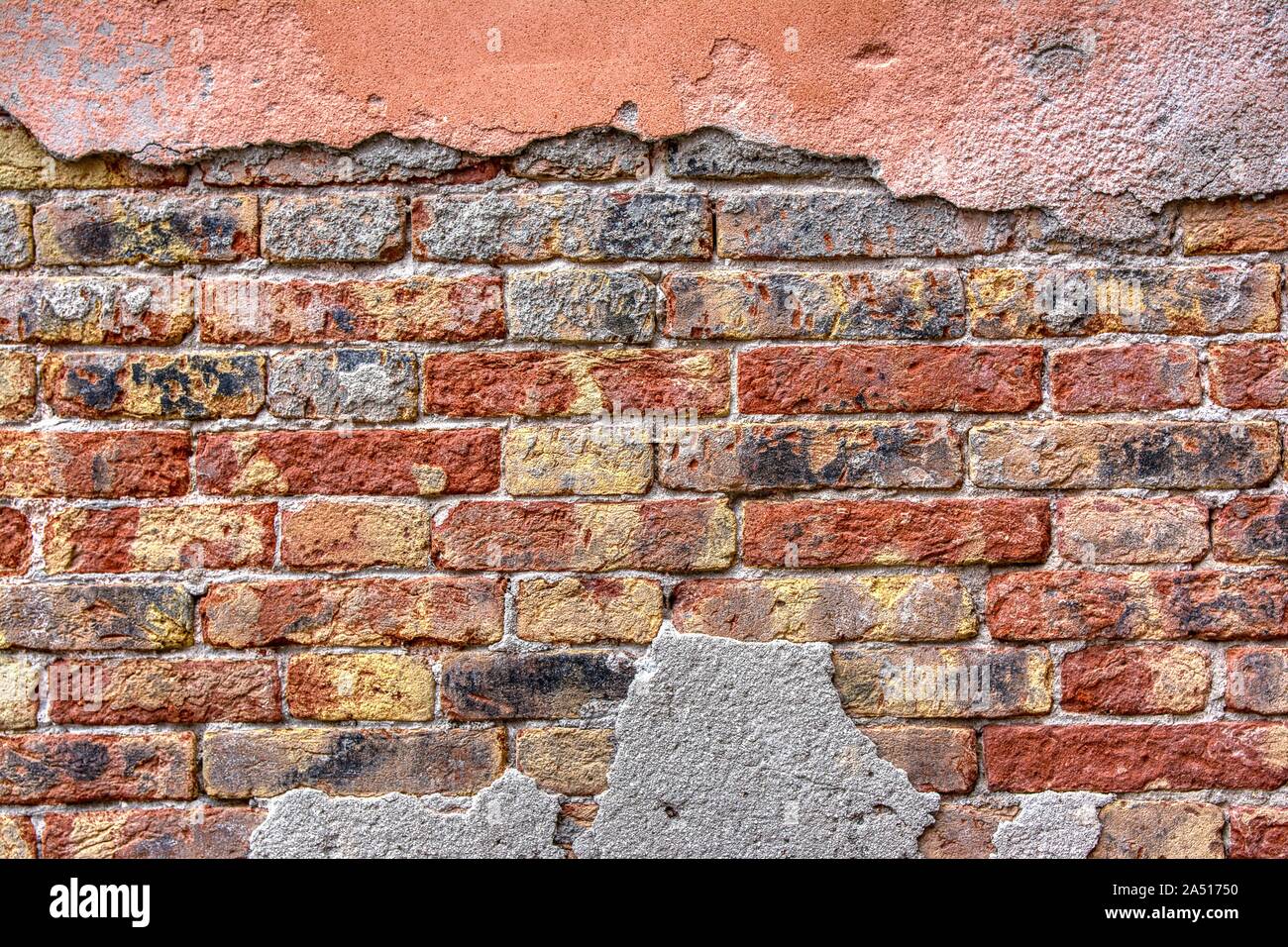 Old brick wall with peeling plaster, grunge background. Stock Photo