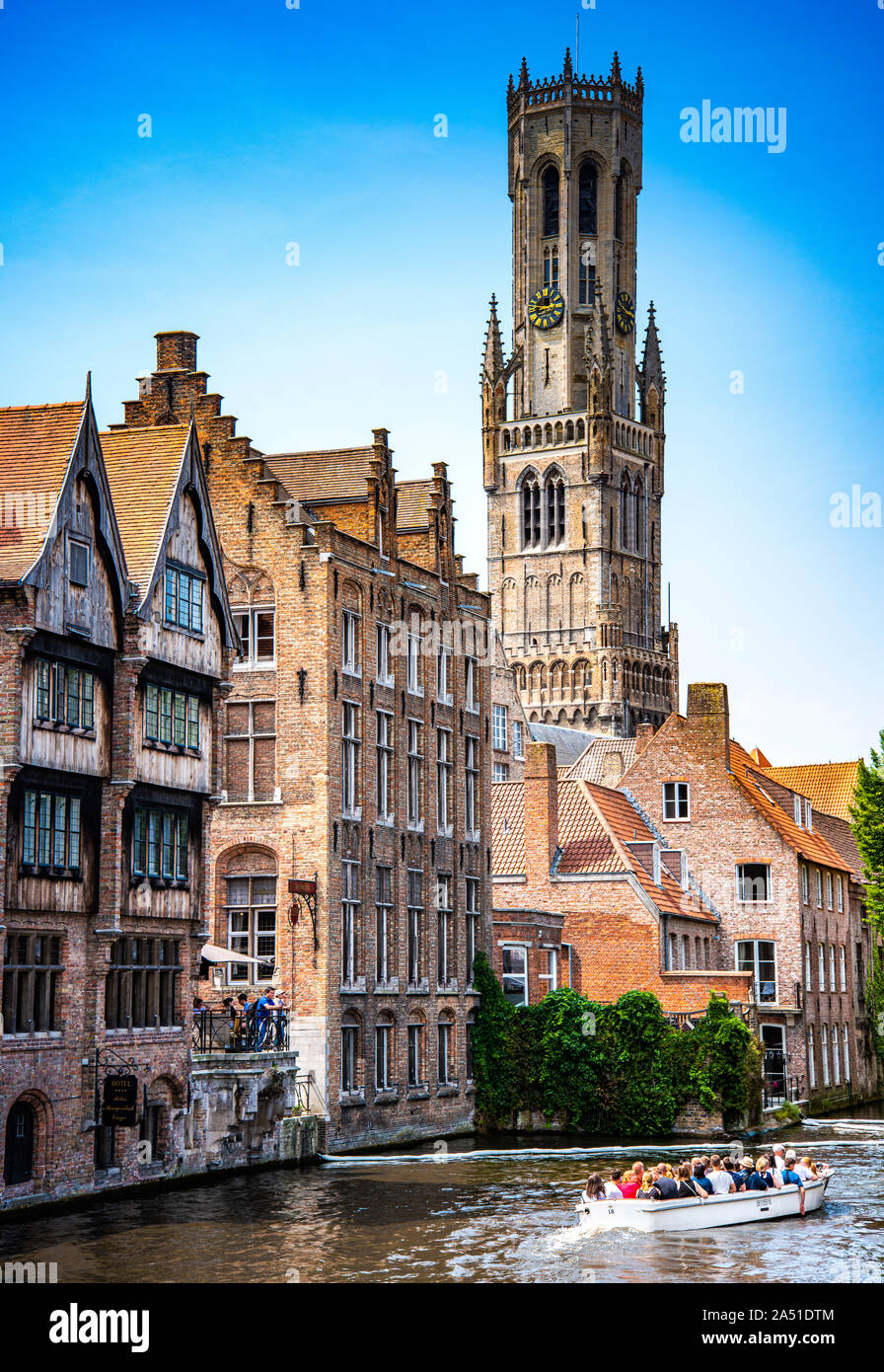 sightseeing boat cruise through Dijver canal surrounded by medieval architecture with Belfort tower in the background, Brugge, West Flanders, Belgium Stock Photo