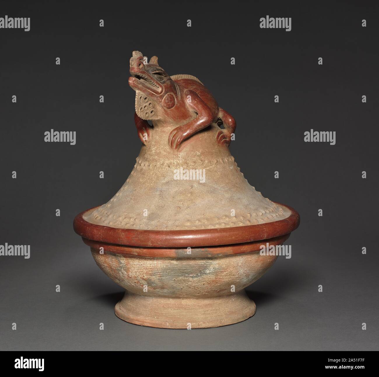 Lidded Bowl with Iguana, c. 600 - 1100. At the time of the Spanish conquest in the 16th century, Costa Rican mythology linked iguanas to the sky and to rulers. The earlier makers of this vessel left no written records, but they may have had similar beliefs. The lizard poses as though basking in the sun, a celestial body, and assumes an aggressive stance that could be likened to a ruler's: the teeth and chin under the dewlap are displayed, Also, fine ceramics like this were buried in the graves of the high-status dead, some of them certainly leaders of the several groups that competed in the ar Stock Photo