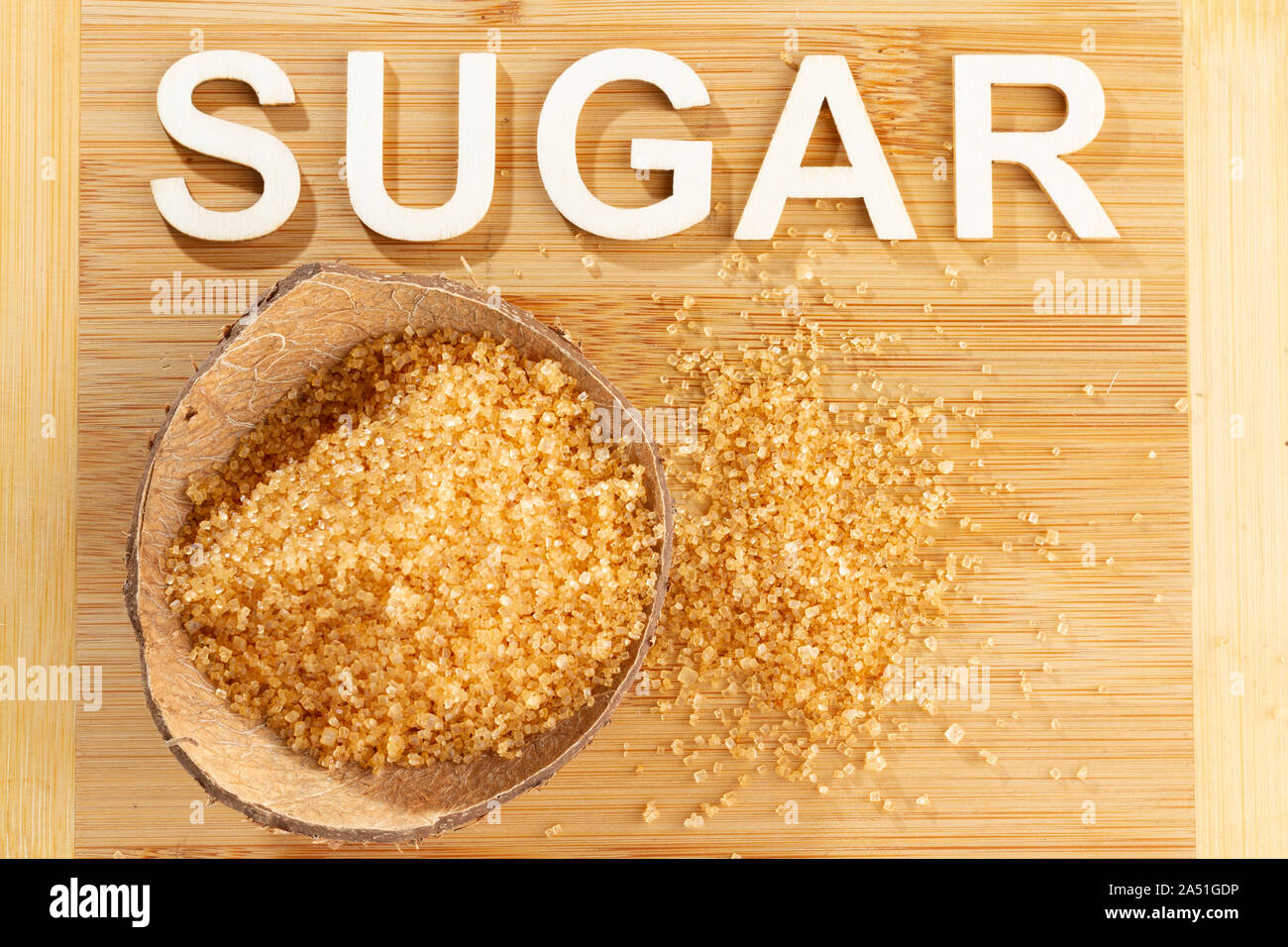 Pile of cane sugar on wooden background, word sugar Stock Photo