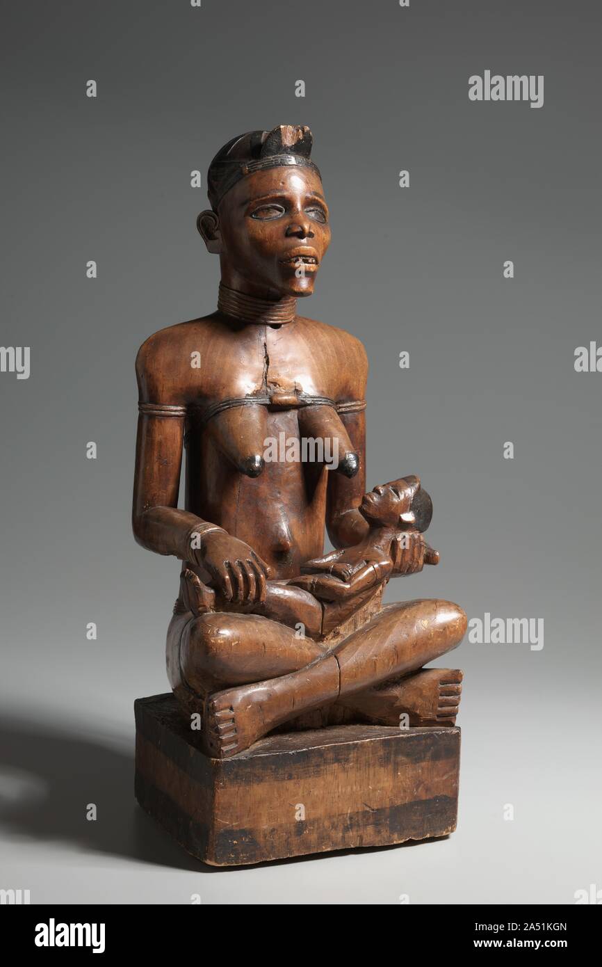 Mother and Child Figure, late 1800s-early 1900s. The Kongo people inhabit a large territory now divided among the nations of Congo, Democratic Republic of Congo, Cabinda, and Angola. The mother and child theme is common in the carving of the Yombe, one of the many Kongo ethnic groups; this example is distinguished by the emotionally powerful expression of the mother's gaunt face. The large size and soft wood of this sculpture indicate a funerary function and placement within a roofed ancestral shrine. The Yombe woman represented was clearly powerful; perhaps her fertility was critical to the s Stock Photo