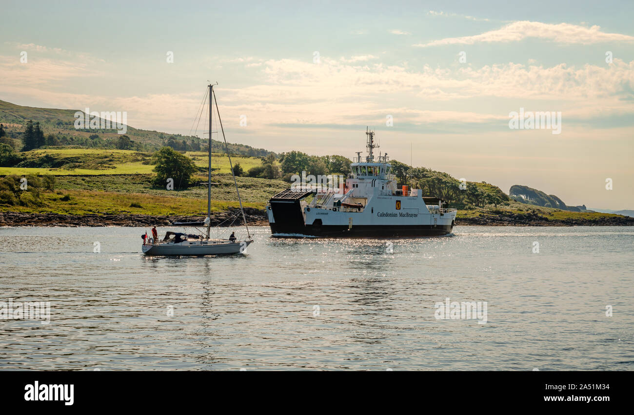 Lochaline / UK: A sailing boat and a ferry in Loch Aline. Loch Aline is a small salt water loch, located in Lochaber, in the Scottish Highlands. Stock Photo