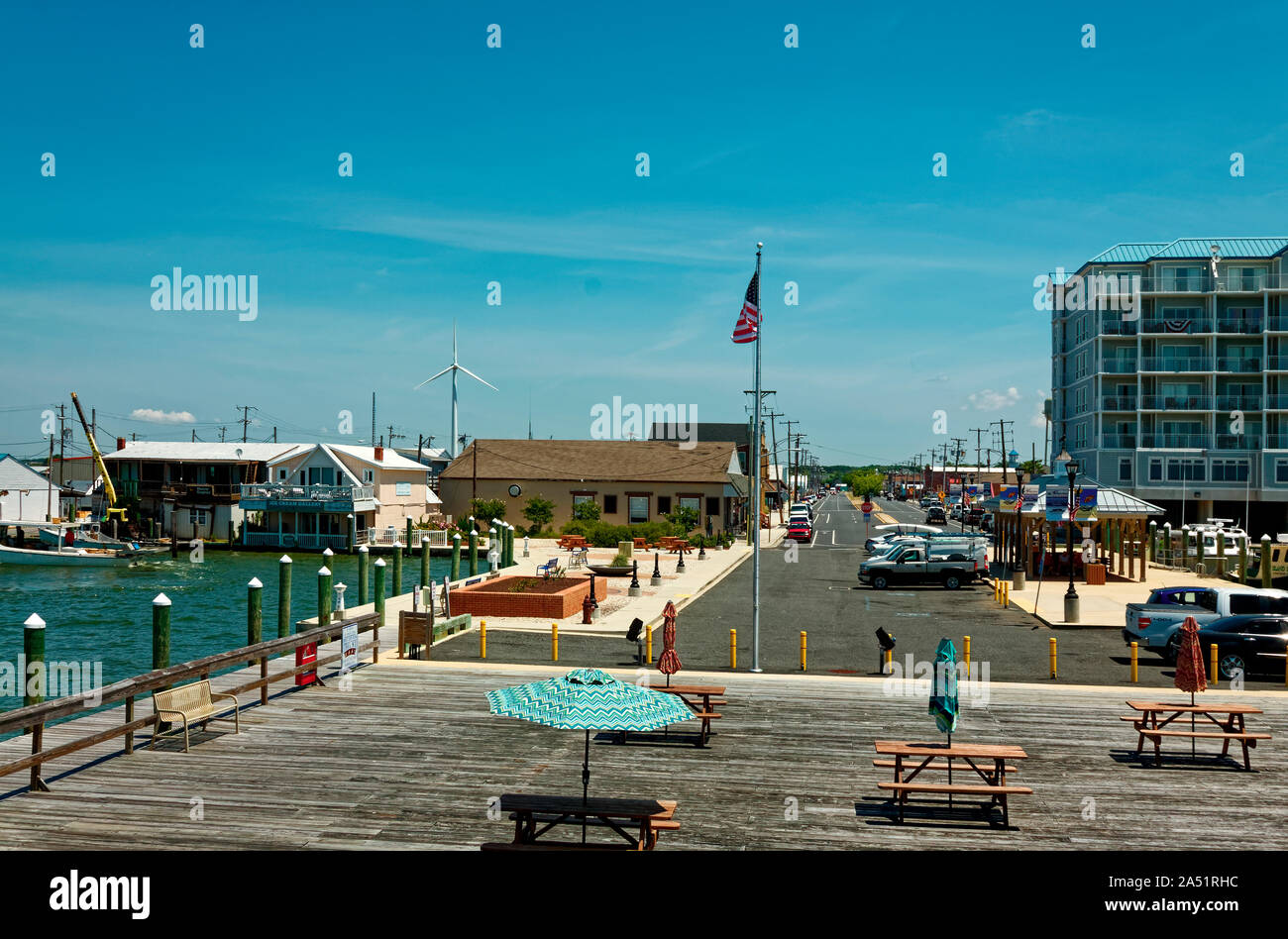 Main Street; town scene; shops; boats, people, vehicles, picnic tables