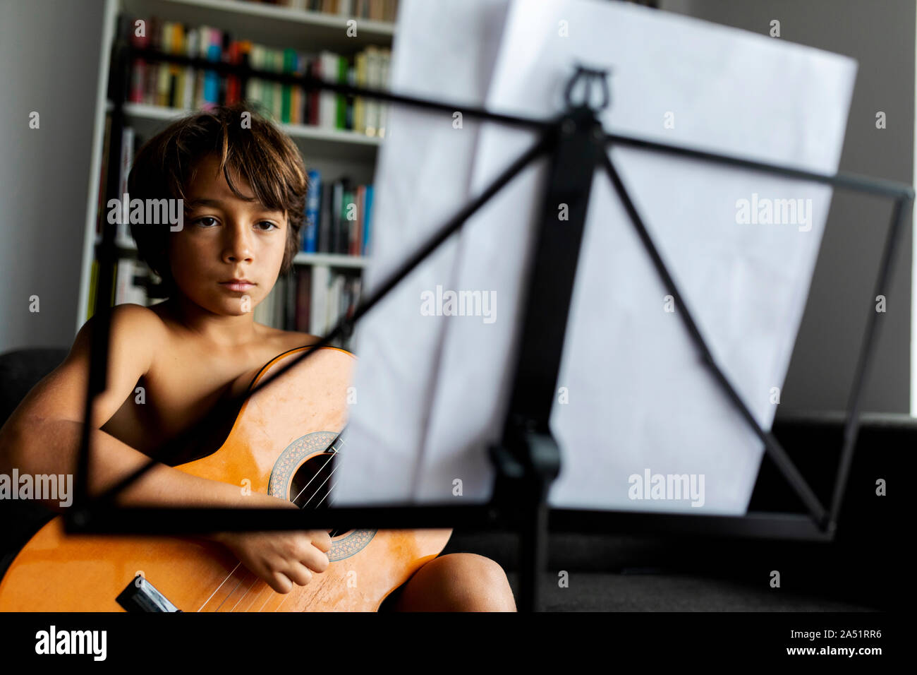 young boy playing guitar in front music stand Stock Photo