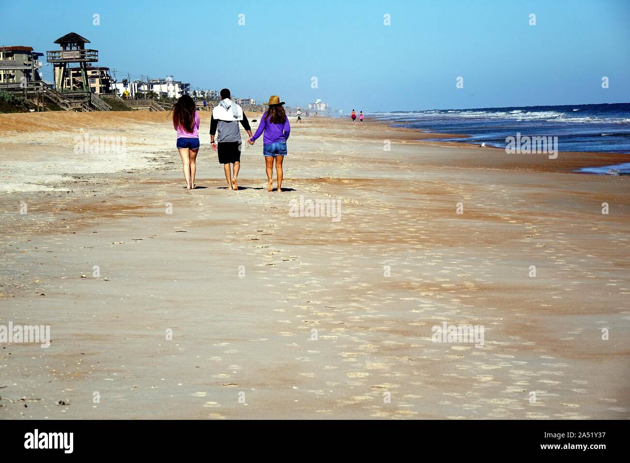 Three young paople taking a stroll on Ormond Beach Stock Photo