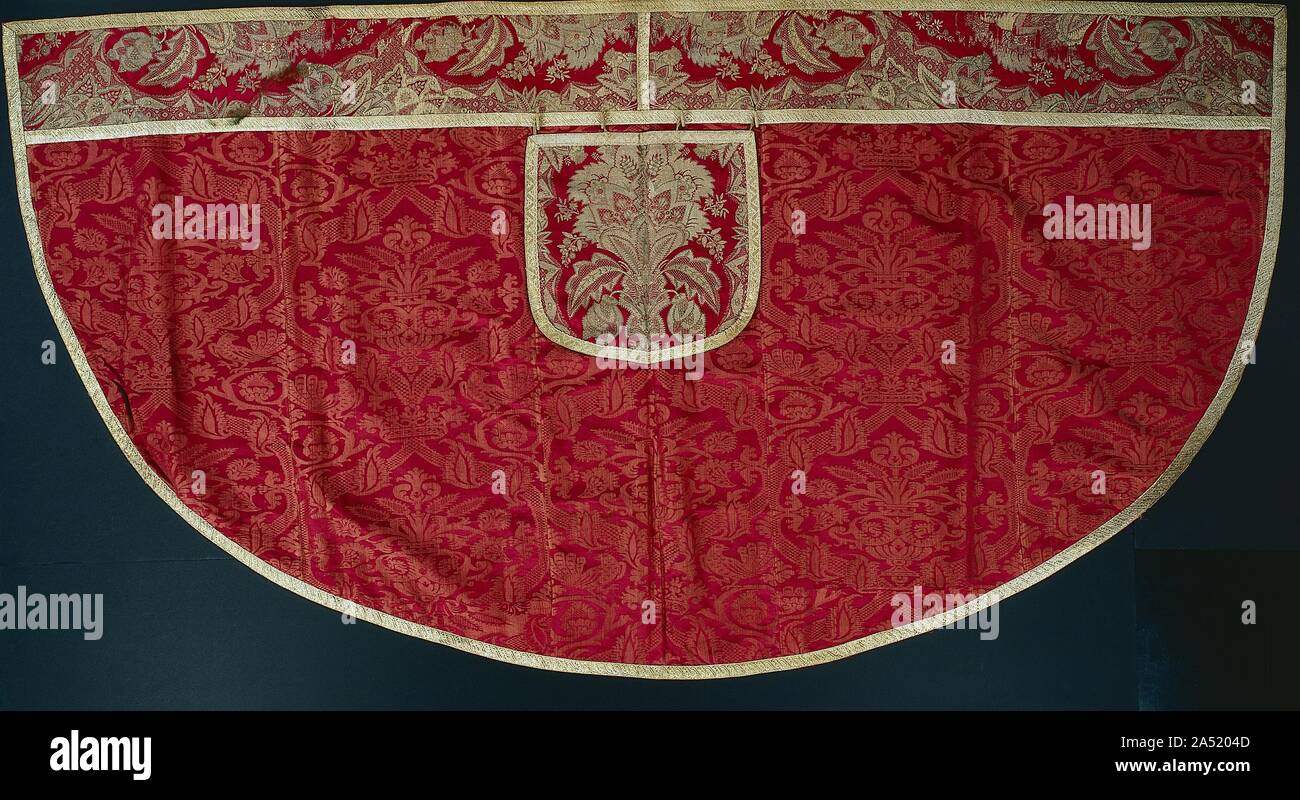 Priest's Red Cope, Orphrey and Hood, late 1500s - early 1600s. Liturgical copes are used for processions especially by those who assist the celebrant. They evolved from a secular outer garment with a hood to protect the wearer from wind and rain. Hoods remained although they became decorative and nonfunctional. This Italian silk damask features large symmetrical bouquets in urns within curved lattices bearing crowns flanked by birds. The French orphrey band, or ornamental border, along the front edges and hood incorporates small ornament associated with prestigious lace amid the formal foliate Stock Photo