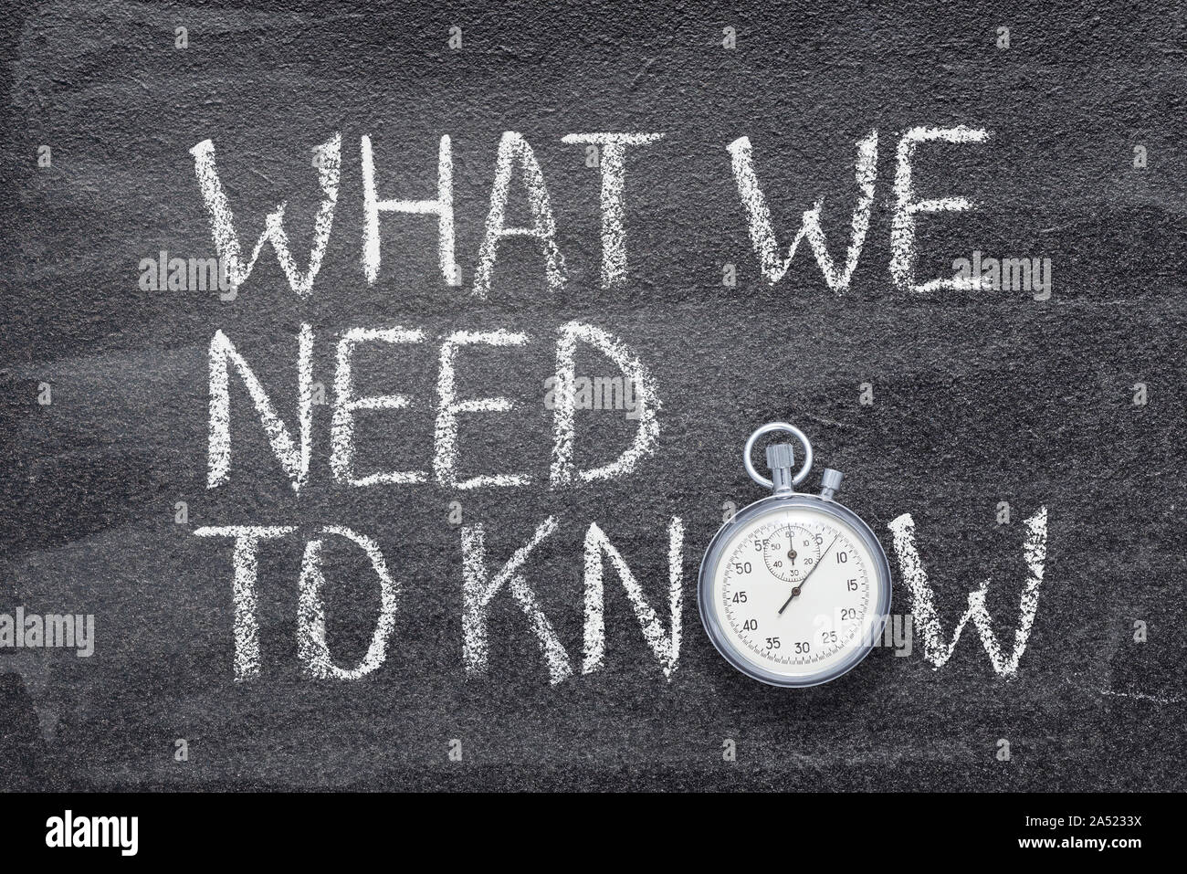 what we need to know phrase written on chalkboard with vintage precise stopwatch Stock Photo