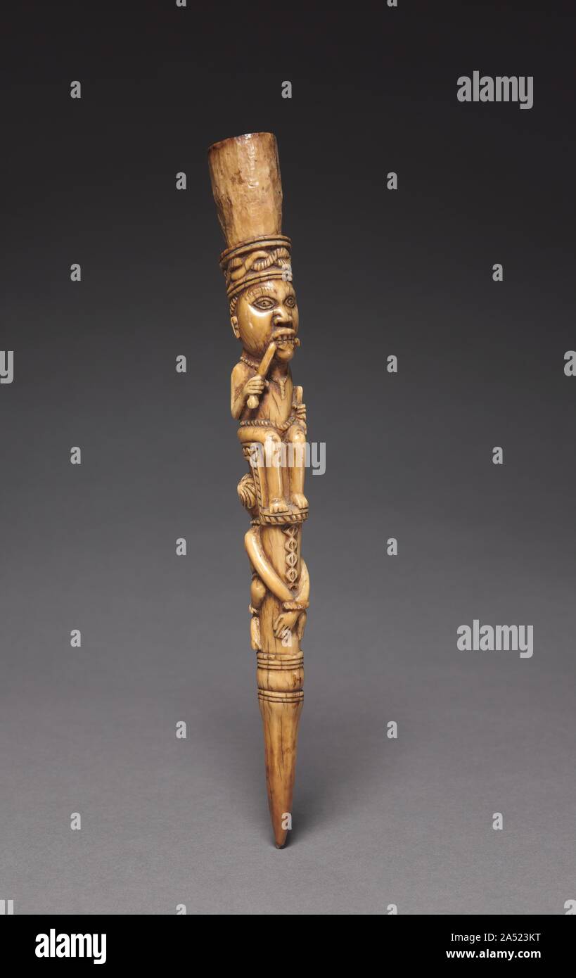 Scepter, late 1800s-early 1900s. Used by male chiefs, ivory scepters were both symbols of status that indicated worldly authority and religious emblems that suggested supernatural influence. In Yombe society until the early 1900s, the aggressive side of a chief&#x2019;s authority was dramatized in spectacular public executions. These scepters depict a chief enthroned on the bound body of a criminal destined for such a death. The use of ivory implies that the chief has the fatal power of an elephant. His hairstyle most likely derives from that worn by Portuguese sailors, and he chews a bitter r Stock Photo