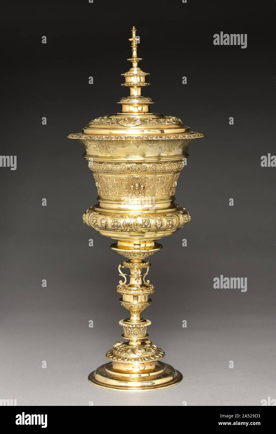 Standing Cup, mid-late 1500s. Large ceremonial silver cups with covers were a status symbol in the late 16th century, particularly when gilded like this superb example from Nuremberg. Stylish and grand, these cups provided the ultimate vessel from which a royal guest or aristocratic visitor could drink at a formal banquet. They came to be known as willkom, or welcome cups, as a result. The lid, mid-section, and base are all cast in sections, creating imposing height and stability for the great amount of silver used, a testament to the skill of the maker and the pocketbook of the owner. Stock Photo
