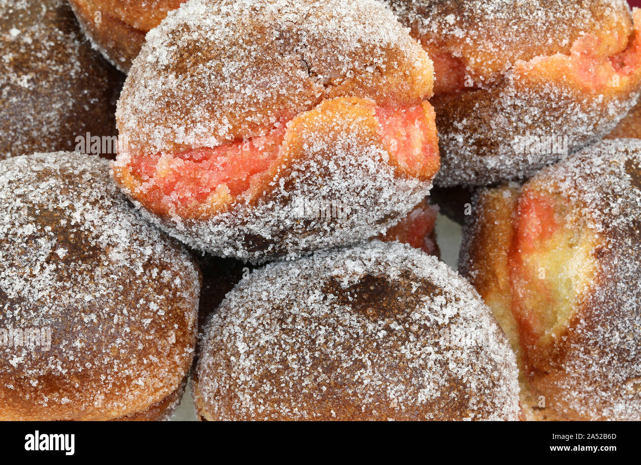 background of many big krapfen with jam alchermes or Alkermes for sale at pastry shop Stock Photo