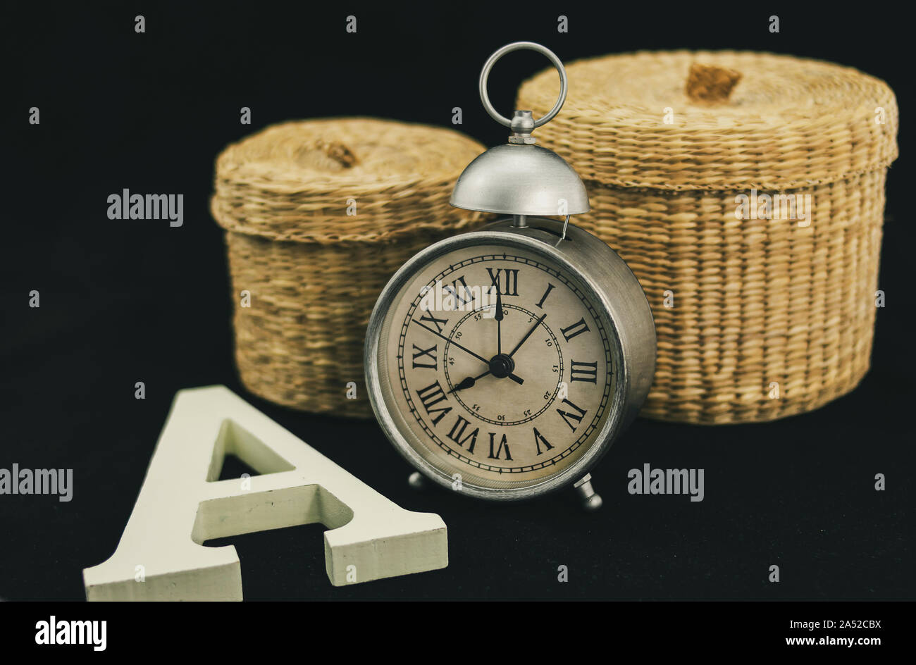 Alarm clock with two wicker boxes and a capital letter A in matt white and corporeal wood Stock Photo