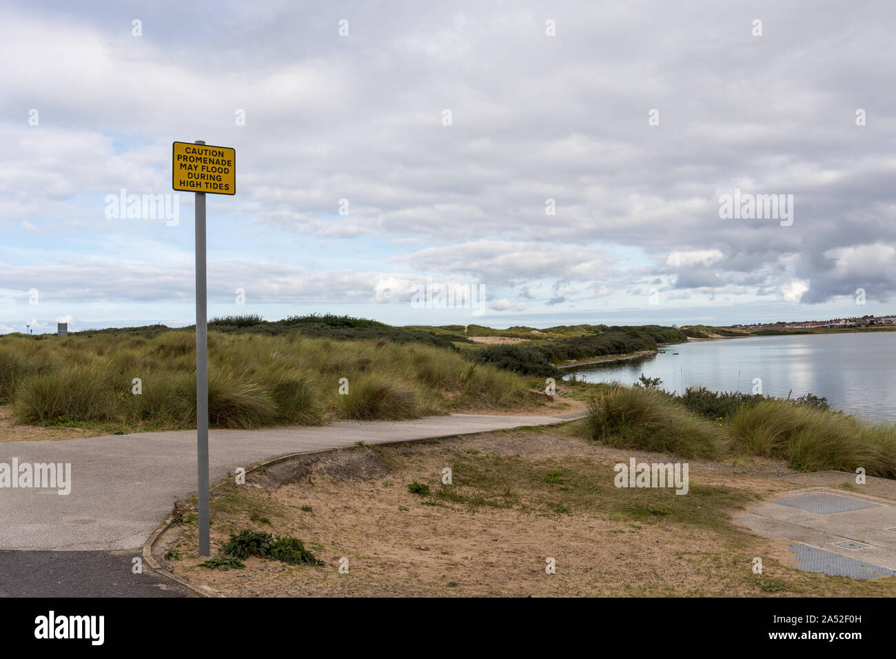 Caution promenade may flood during high tides warning sign at Crosby Lakeside Adventure Centre, Merseyside, United Kingdom Stock Photo