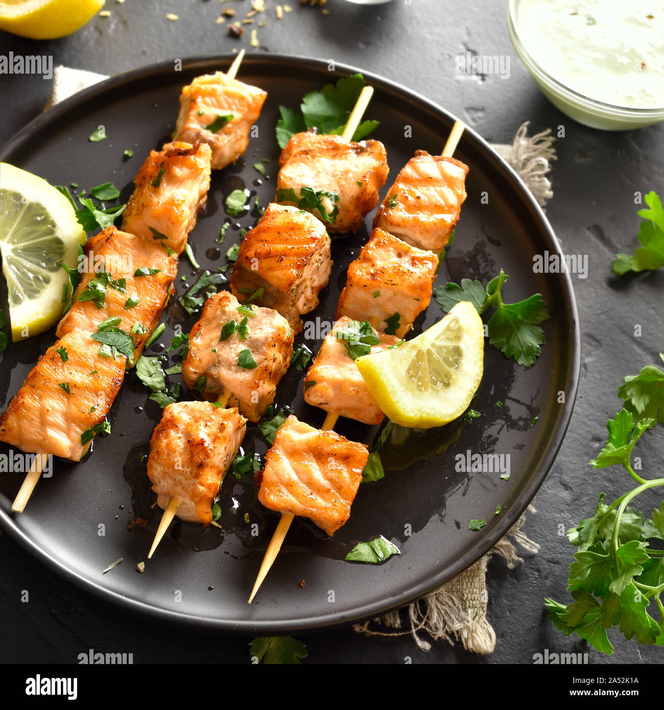 Close up of grilled salmon kebab. Barbecue salmon skewers on black