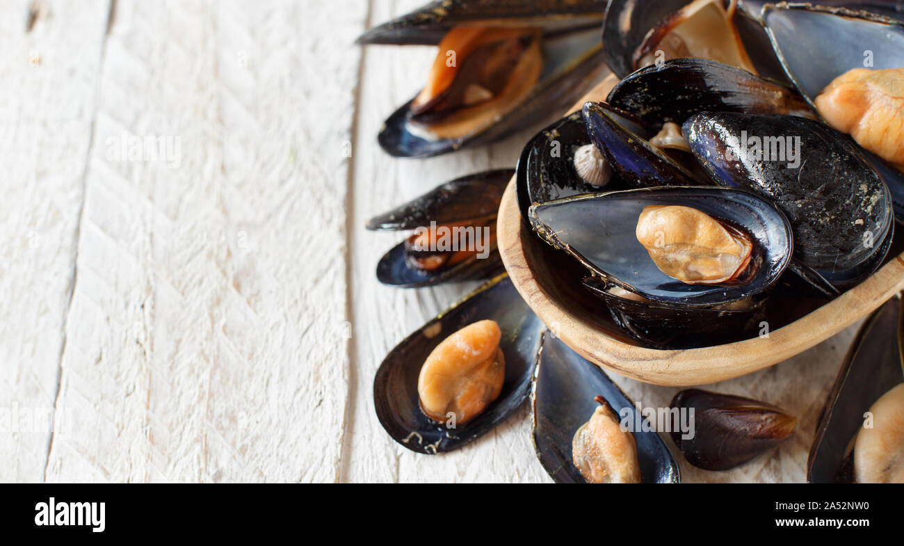 Fresh boiled  italian black mussels close up on a white wooden table Stock Photo