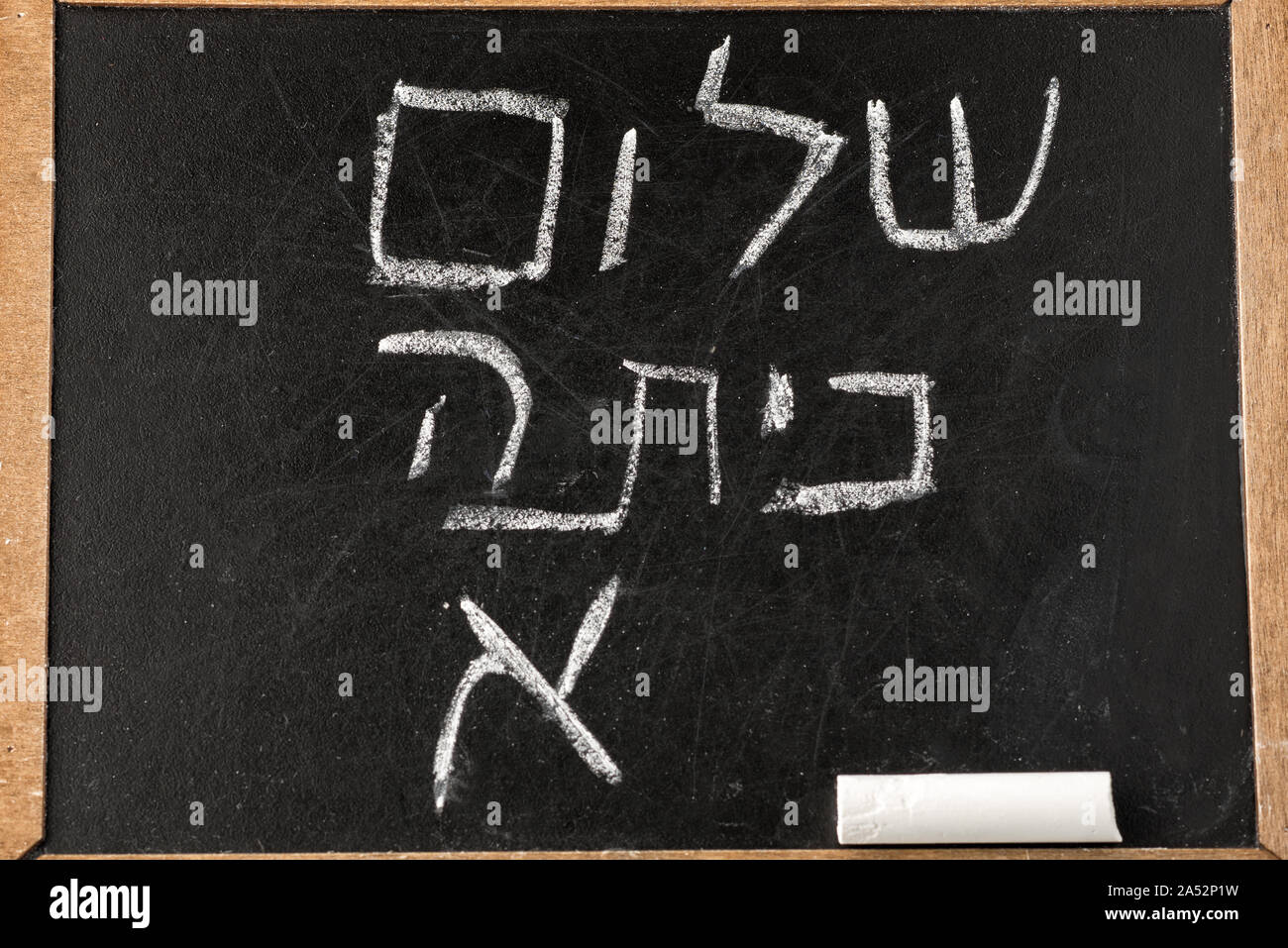 Back to School. Blackboard or chalkboard with Hello First Grade class greetings in Hebrew Shalom Kita Alef written with white chalk on the black board. Stock Photo