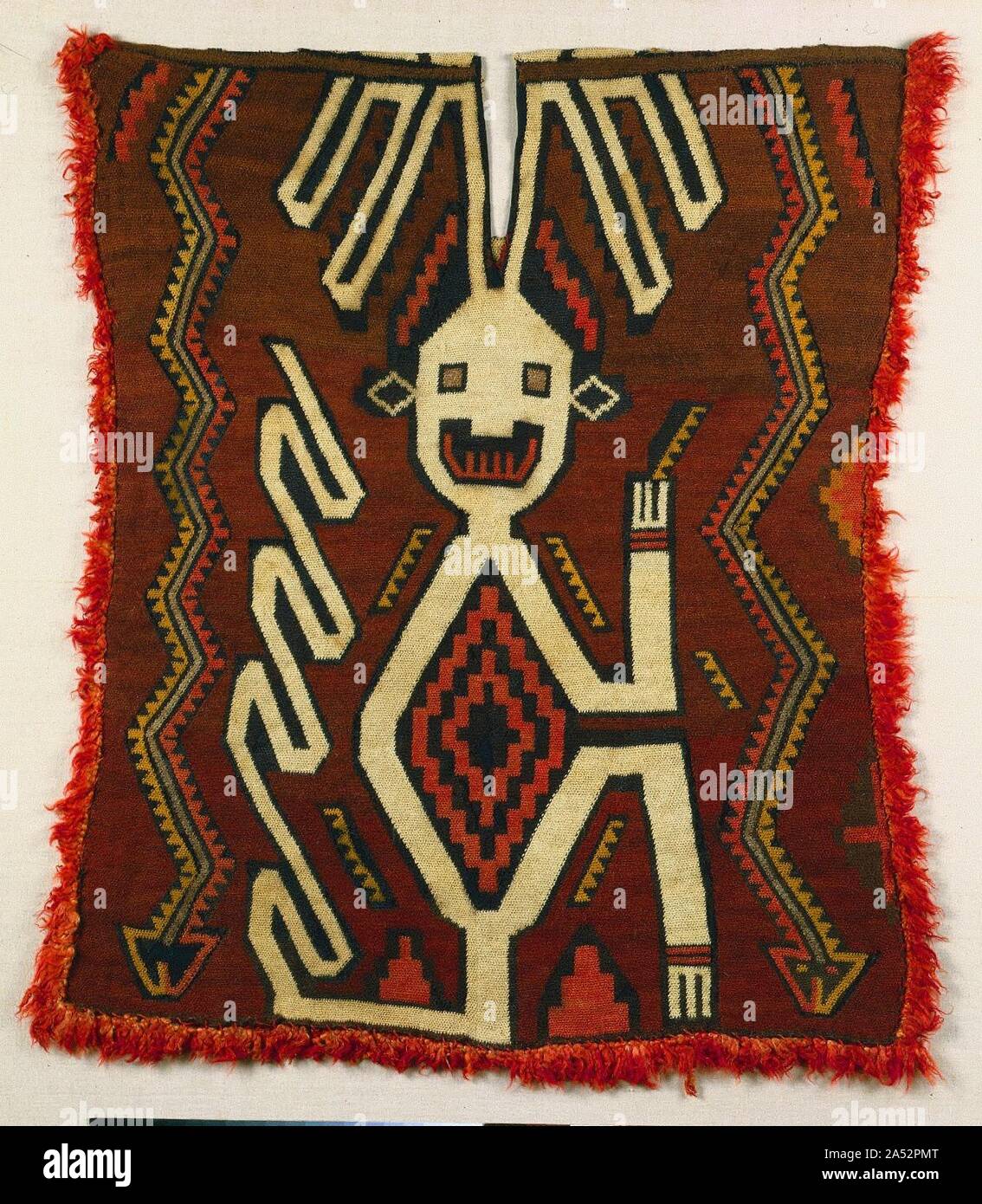 Tunic, 400-200 BC. The striking, large-scale figure shown on this tunic has an elaborate, monkey-like tail as well as head appendages that mark the creature as supernatural. This tunic, a relatively rare type, was made not on a loom but rather by working the yarns into loops with a needle. It is made entirely with camelid fiber, which can readily be dyed in a range of vivid colours. The fiber comes from one of the four camels (camelids) native to the Andes Mountains&#x2014;the alpaca and llama, both domesticated, and the wild guanaco and vicu&#xf1;a. On the coast, it represents a prestige impo Stock Photo