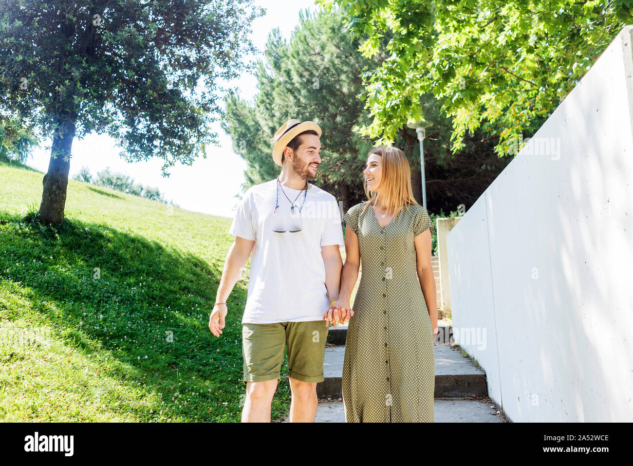 Happy young couple walking in a park holding hands Stock Photo