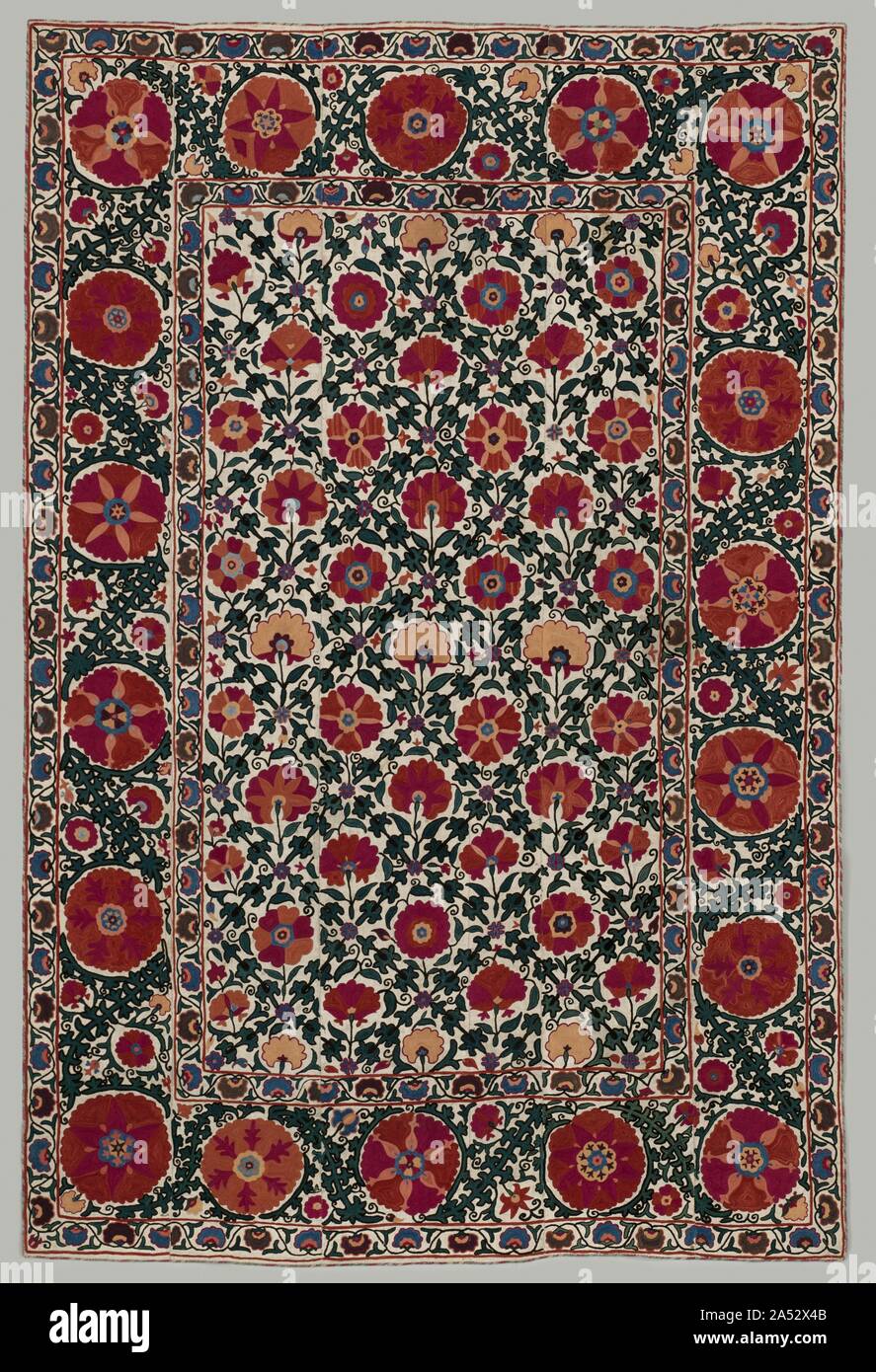 Wall Hanging, 1850-1899. Embroideries known as suzani, after the Persian and Tajik word for needle (suzan), feature bold floral and foliate motifs enriched with several shades of red and crimson silk thread. This example suggests a lush garden enriched with single flowering plants alternating with a bird&#x2019;s-eye view of blossoms in a foliate diamond trellis. Either a skilled family member or a professional drew the pattern in black ink (still visible) on five loosely joined cotton cloths; female family members disassembled them for stitching and reassembled them upon completion. Suzanis w Stock Photo
