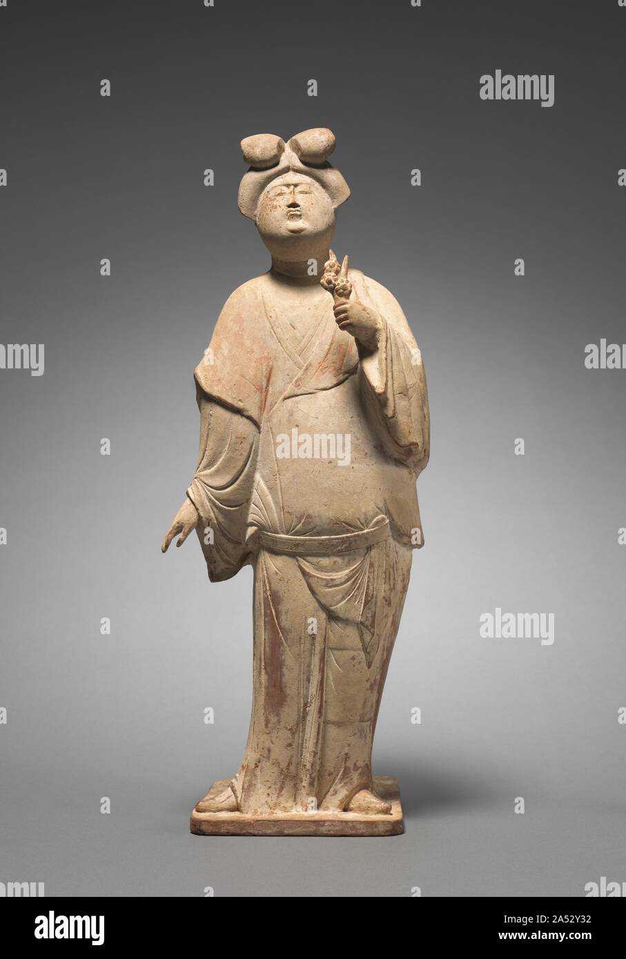 Woman Holding Plum Blossoms, mid 700s. Tang figurines placed in the tombs give a vivid picture of everyday life. Images of elegant ladies in various hairstyles, costumes, and activities suggest the fashion of the time. This example of a plump and flamboyant lady is a common type found in mid-8th-century tombs, especially in the cosmopolitan city of Xian. Together with other figurines&#x2014;court officials, musicians, dancers, hunters, foreign travelers, horses, camels, guardian warriors, and guardian animals&#x2014;such tomb sculptures accompanied the deceased in the afterlife. Stock Photo