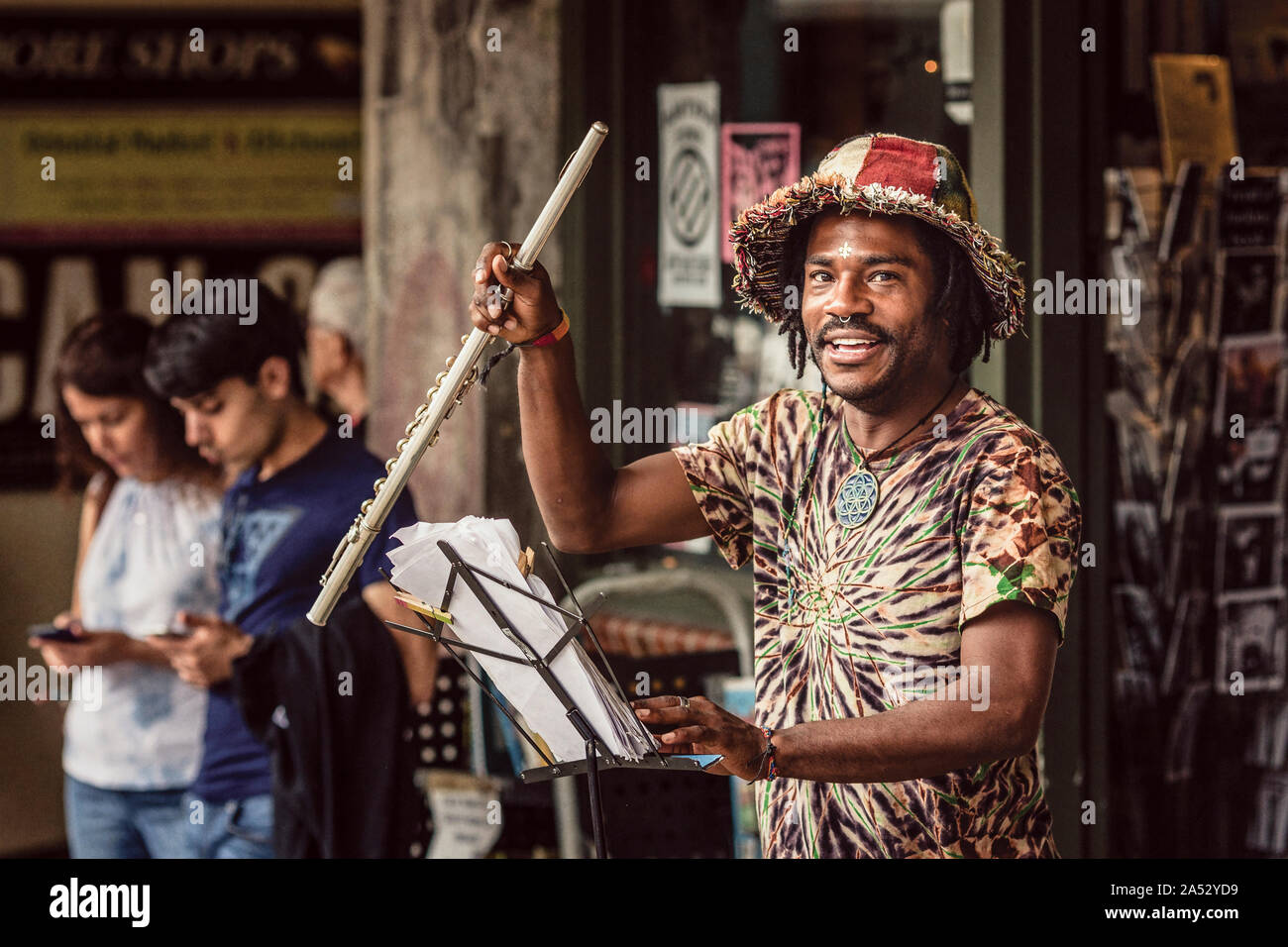 Street musician plays flute at Pike Place Market while kids on phones Stock Photo