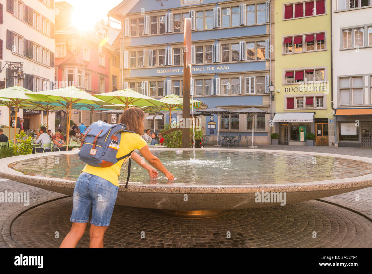 Woman refreshing her hands in Munsterhof fountain, Zurich famous square, Switzerland Stock Photo