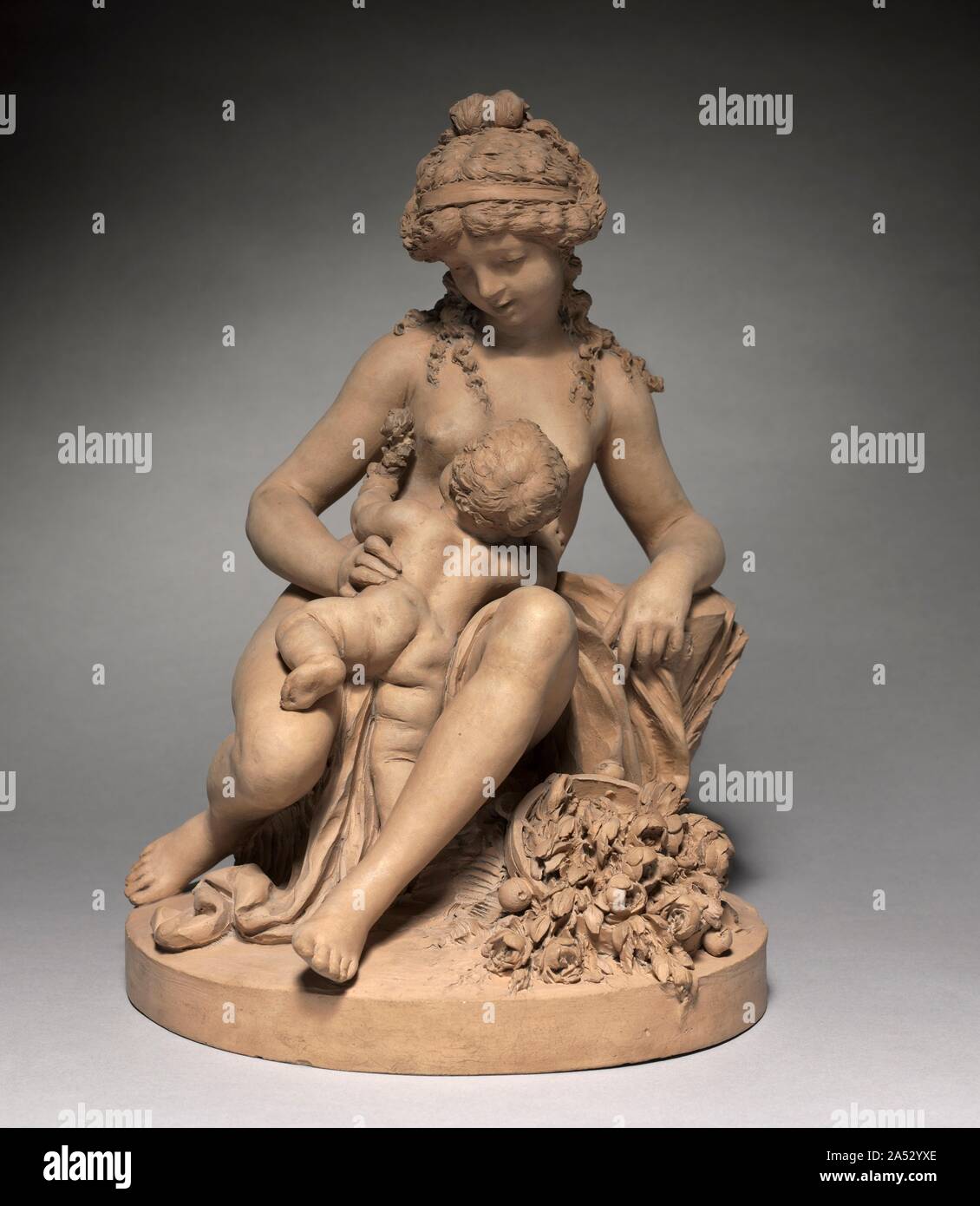 Young Woman and Child at Play, 1780s. The French sculptor Claude Michel, called Clodion (1738-1814), constructed much of his work in terracotta. After firing, the unglazed colour of the clay can vary widely, so each of Clodion's works in this medium has a slightly different hue, in this case a smooth reddish gray. Clodion depicts a mother nursing her newborn with painstaking attention to detail, from the tendrils of hair that cascade gracefully down to the mother's shoulders to the brilliant bouquet at the pair's feet. Stock Photo