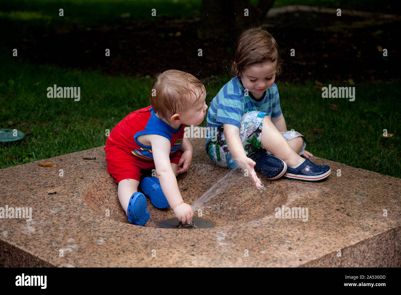 Two little boys play in a water fountain located at the Smithsonian Arts and Industries Building grounds Stock Photo