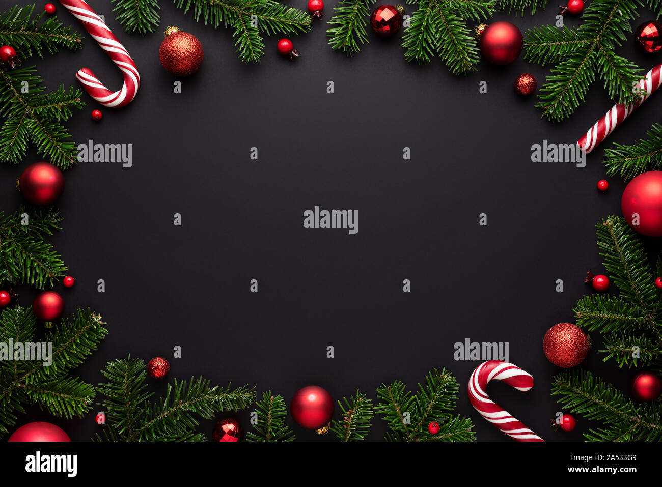Black Christmas background. Decorative oval frame of fir branches, Christmas balls and Candy canes. Copy space for text Stock Photo
