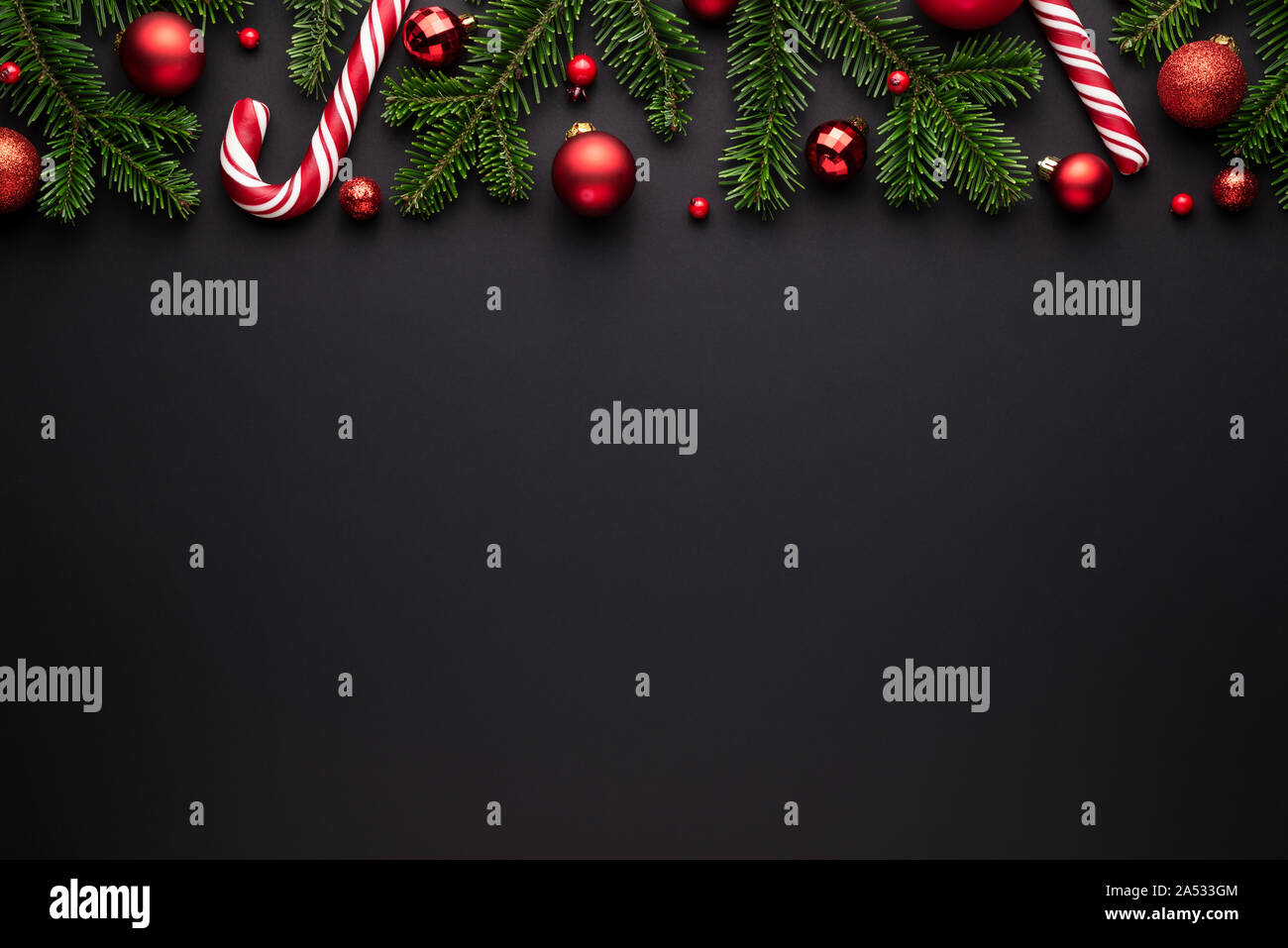 Black christmas background. Festive border of fir branches, Christmas balls and candy canes Stock Photo